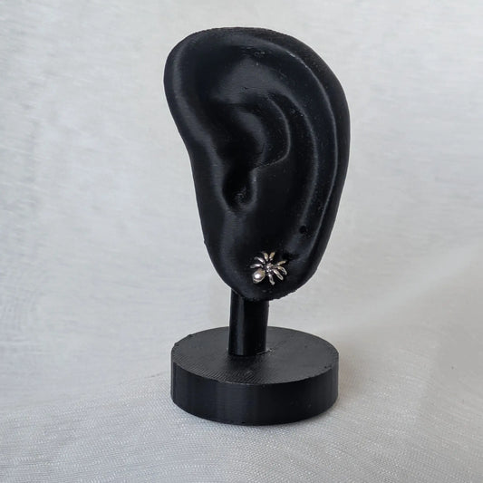 Realistische Darstellung der Spinnen-Ohrstecker getragen an einem schwarzen Schmuck-Display.