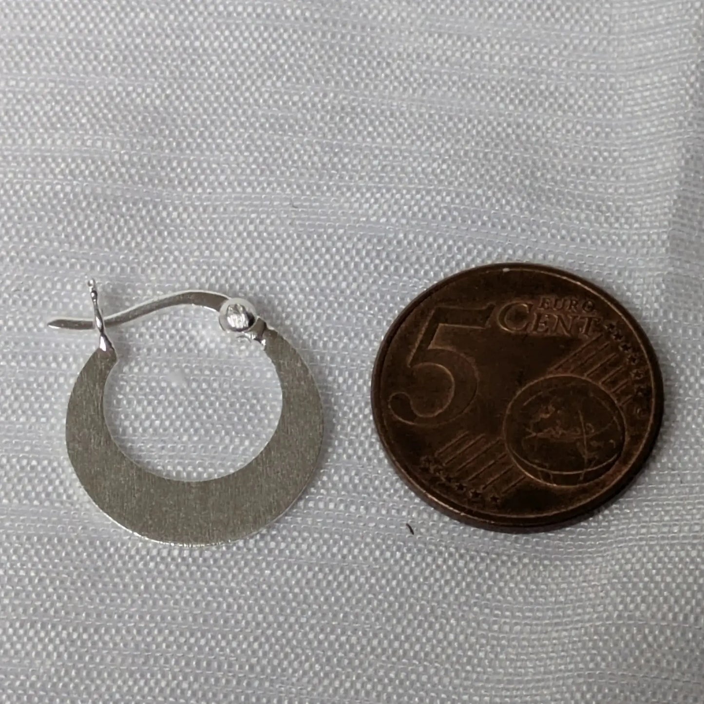 Größenvergleich der sichelförmigen Silber-Creolen auf einer 5-Cent-Münze.