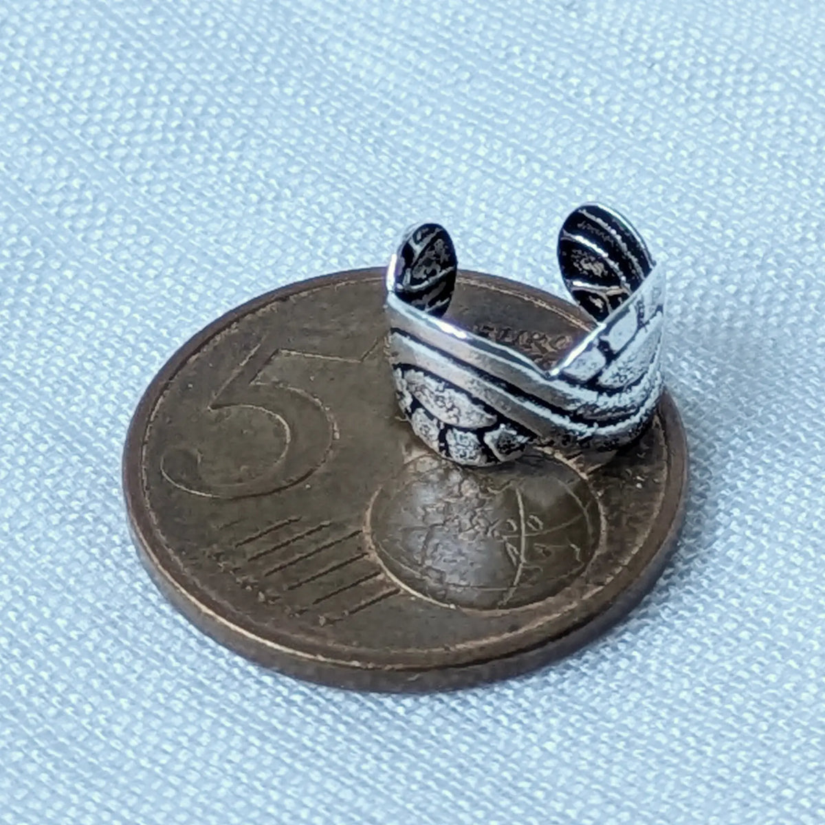 Der Vintage-Silber Ear Cuff liegt auf einer 5-Cent-Münze, um die kompakte Größe des Schmuckstücks im Größenvergleich deutlich zu machen.