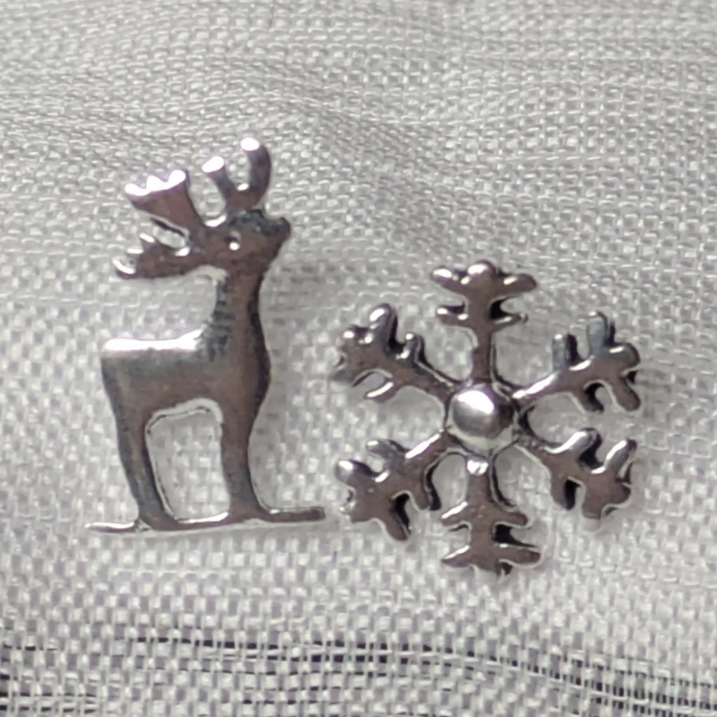 Detailansicht der asymmetrischen 925 Silber Ohrstecker mit Hirsch- und Schneeflocken-Motiv.