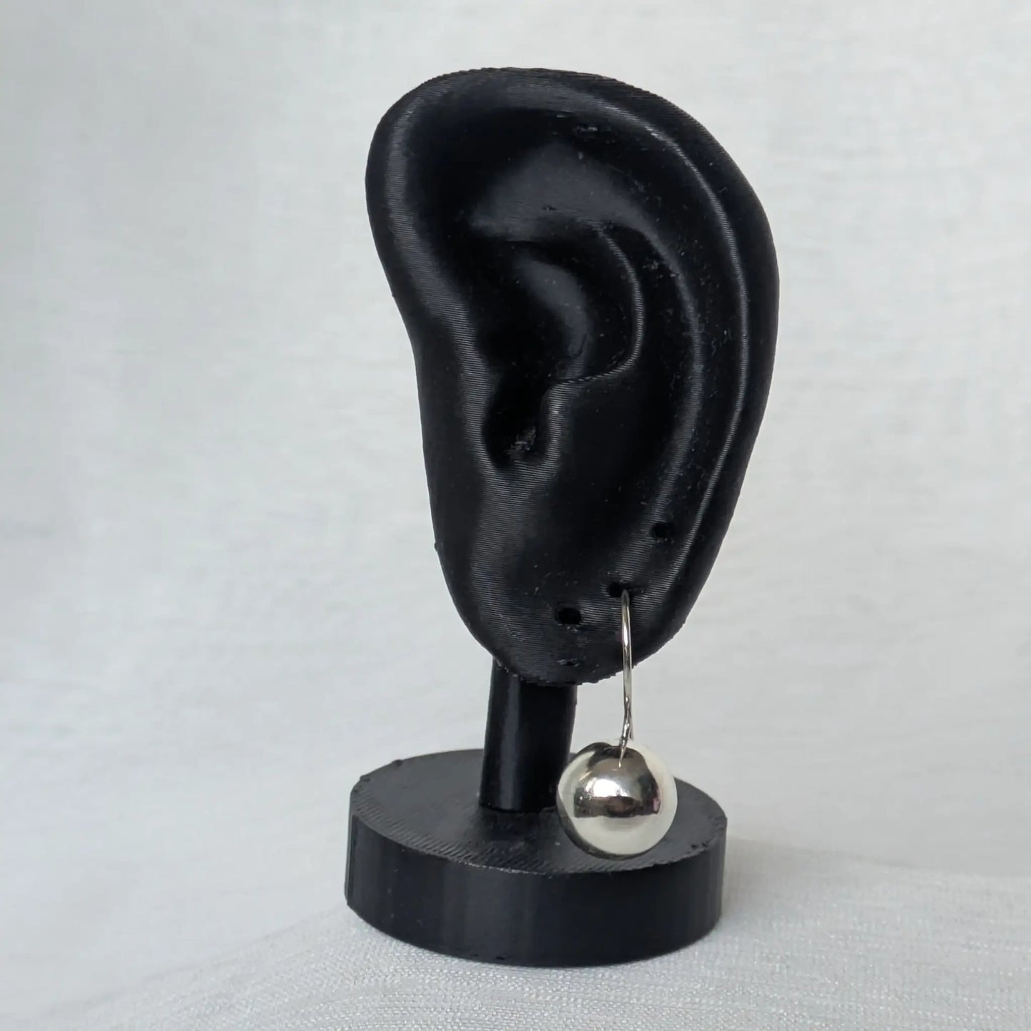 Elegante Präsentation der 12mm Kugel Ohrhänger Silber am schwarzen Display-Ohr.