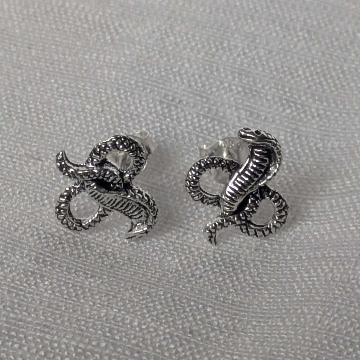 Elegante Kobra Schlangenstecker aus Sterling Silber auf weißem Stoffhintergrund.