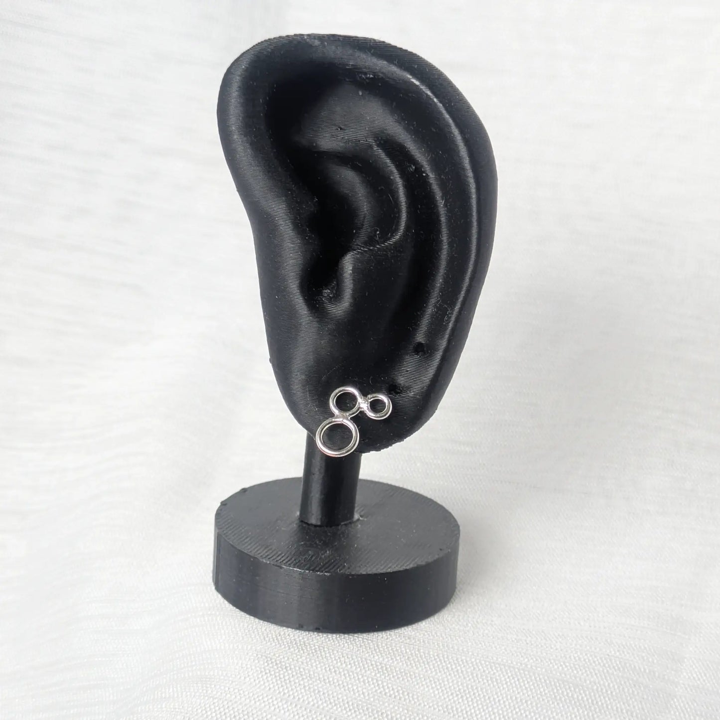 Triple-Ring Silberohrringe präsentiert an einem eleganten schwarzen Display.