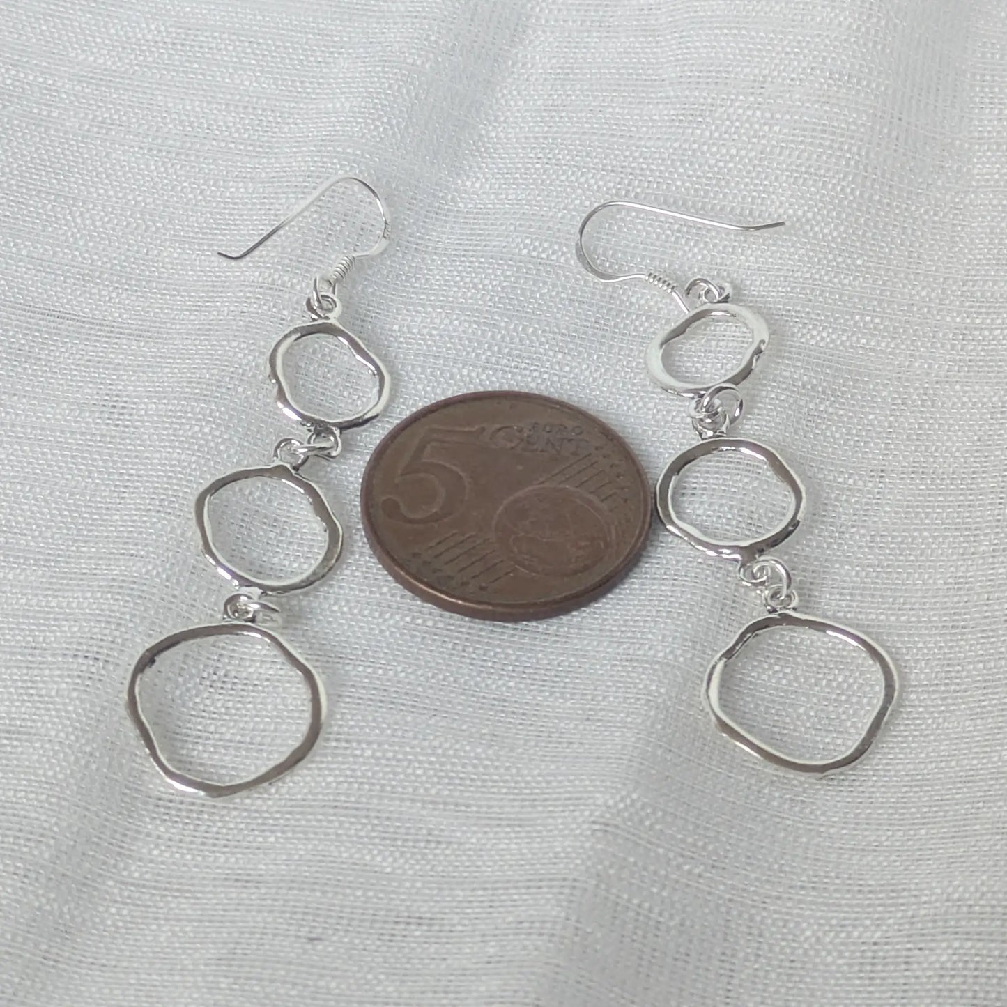 Gehämmerte Silberohrringe, die neben einer 5-Cent-Münze zum Größenvergleich platziert sind.
