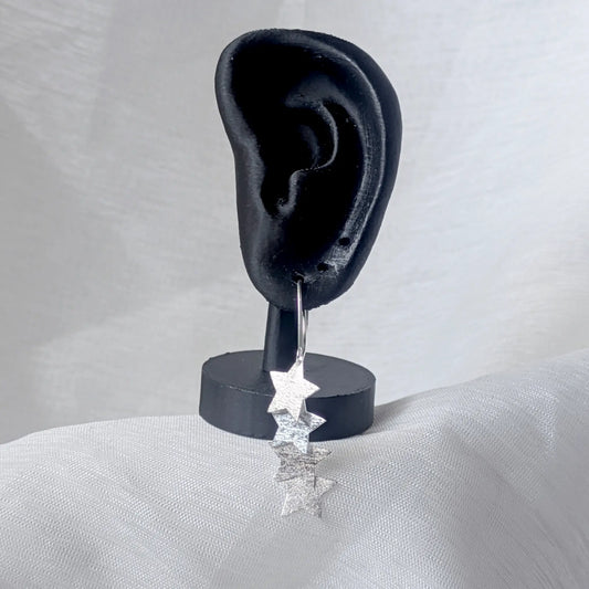 Lange Stern-Ohrhänger aus Silber getragen an einem schwarzen Ohr-Display, um den eleganten Fall der Kaskade am Ohr zu demonstrieren.