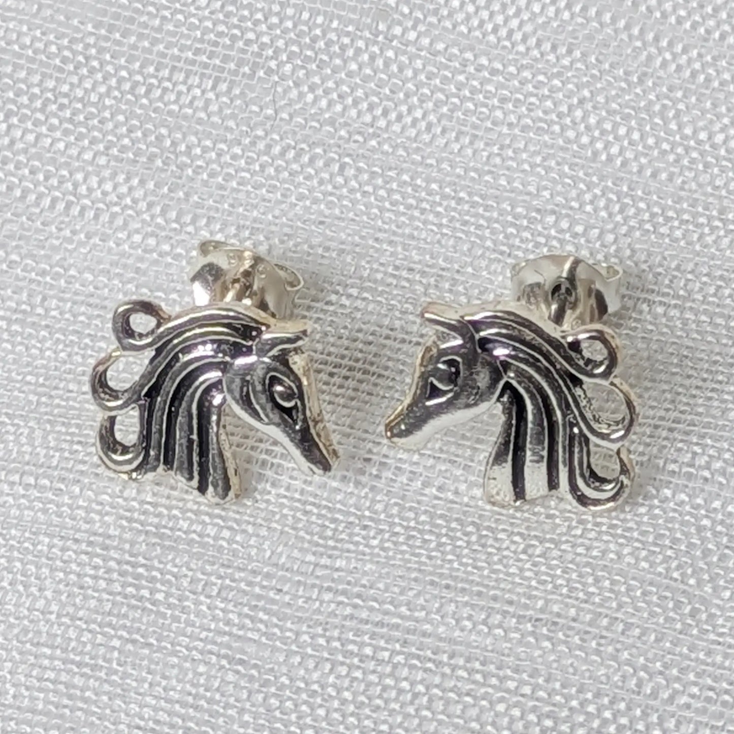 Frontalansicht der glänzenden Silber-Ohrringe mit Pferdekopf-Motiv.