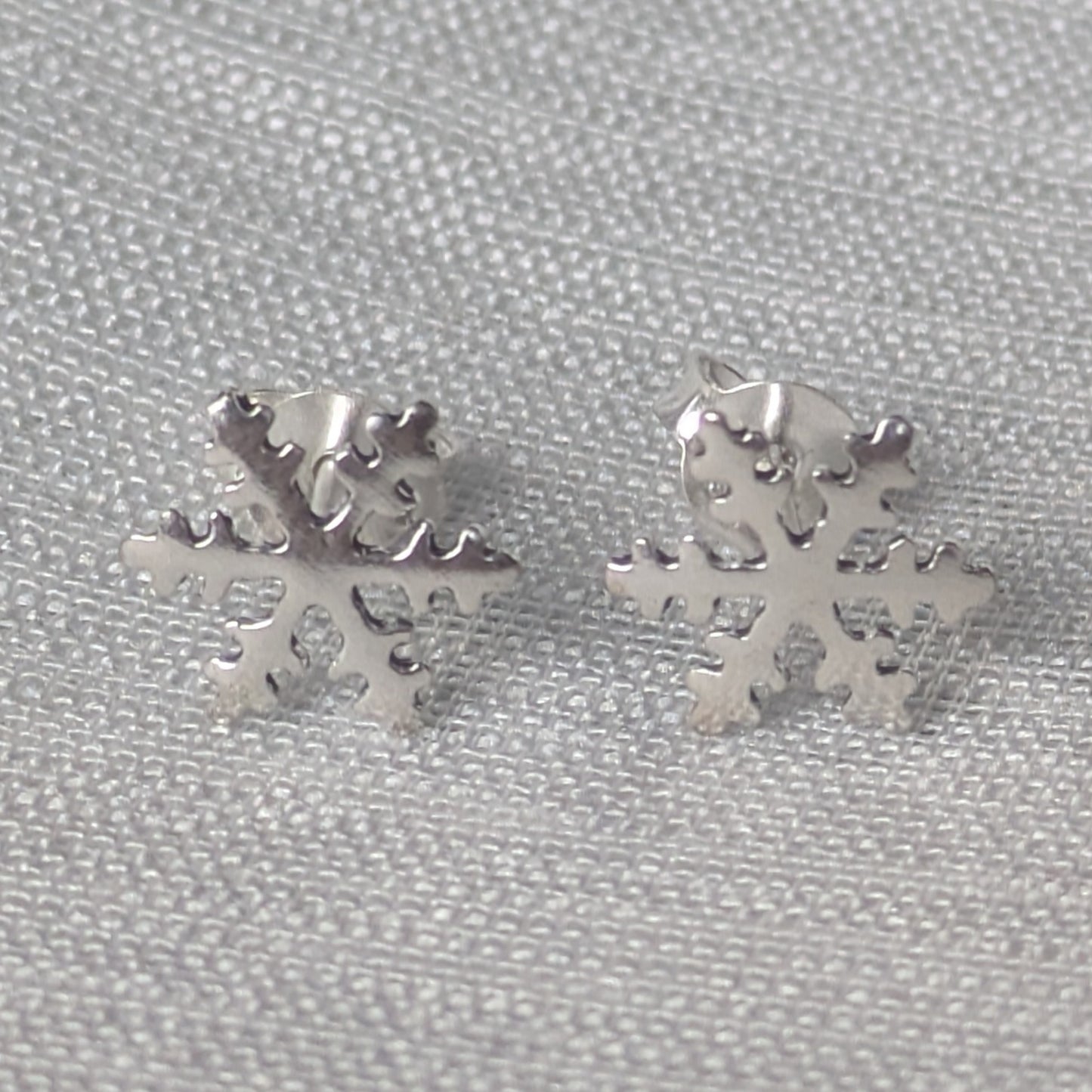 Frontalansicht der glänzenden Schneeflocke Ohrstecker aus 925 Sterling Silber auf hellem Hintergrund.