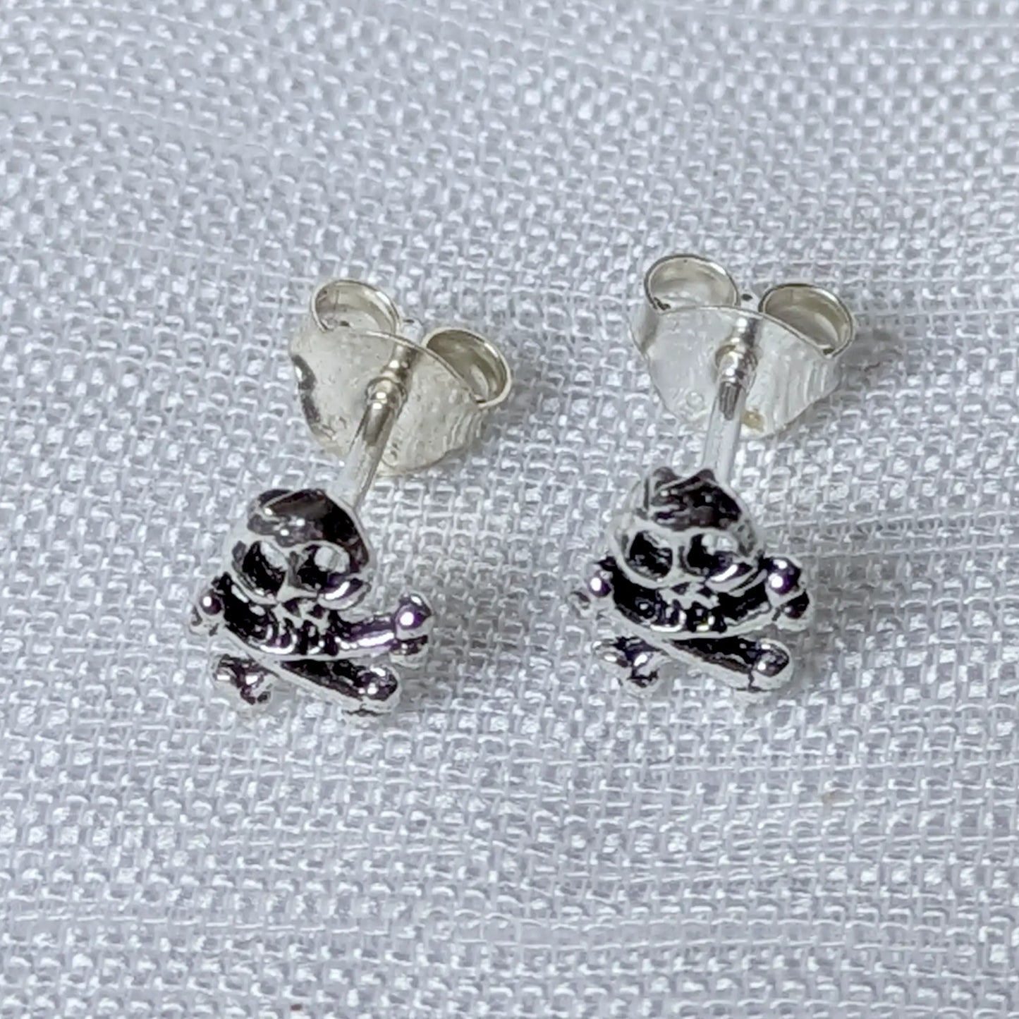 Frontalansicht der silbernen Skull Ohrstecker mit gekreuzten Knochen.`