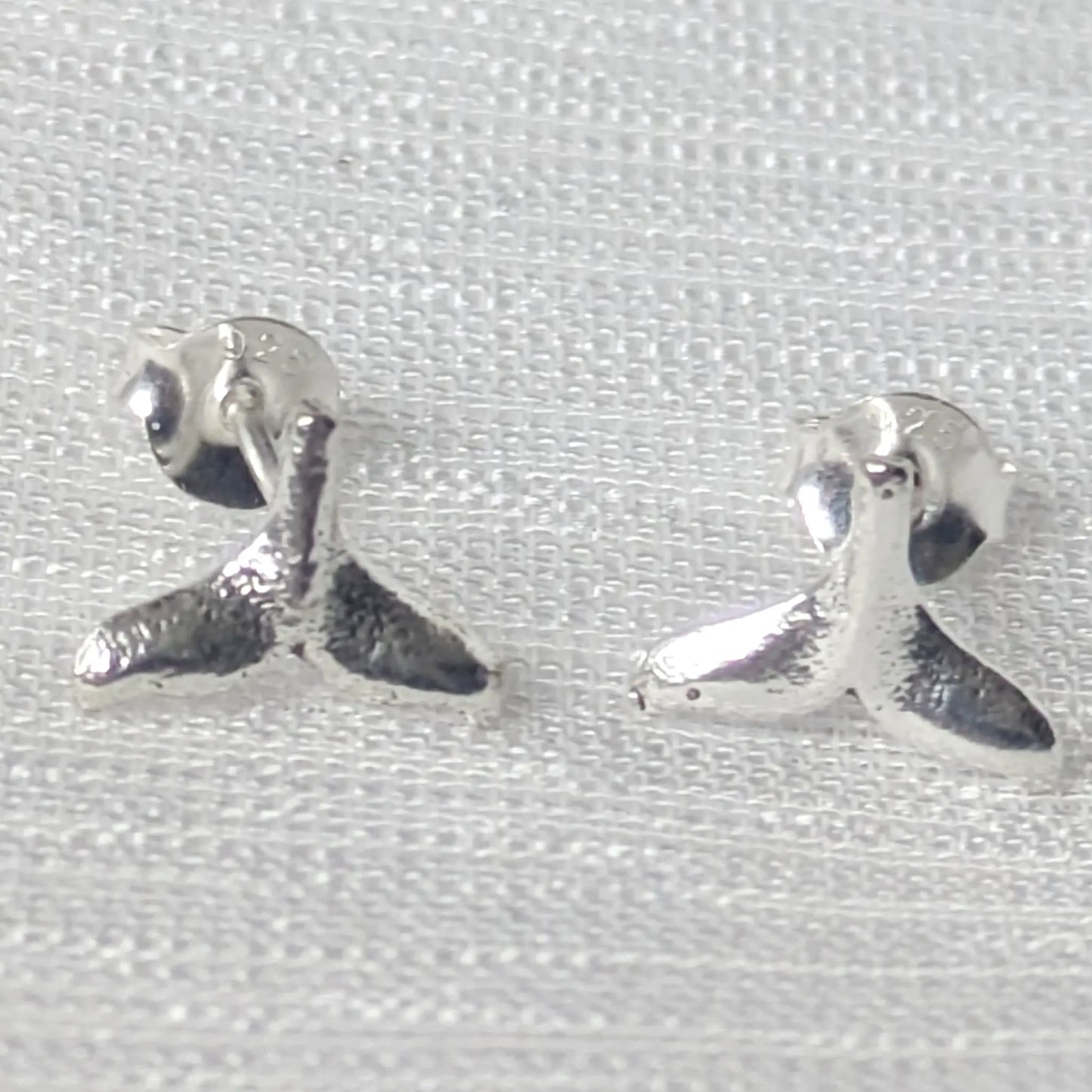 Frontansicht silberne Walflosse Ohrstecker auf weißem Hintergrund