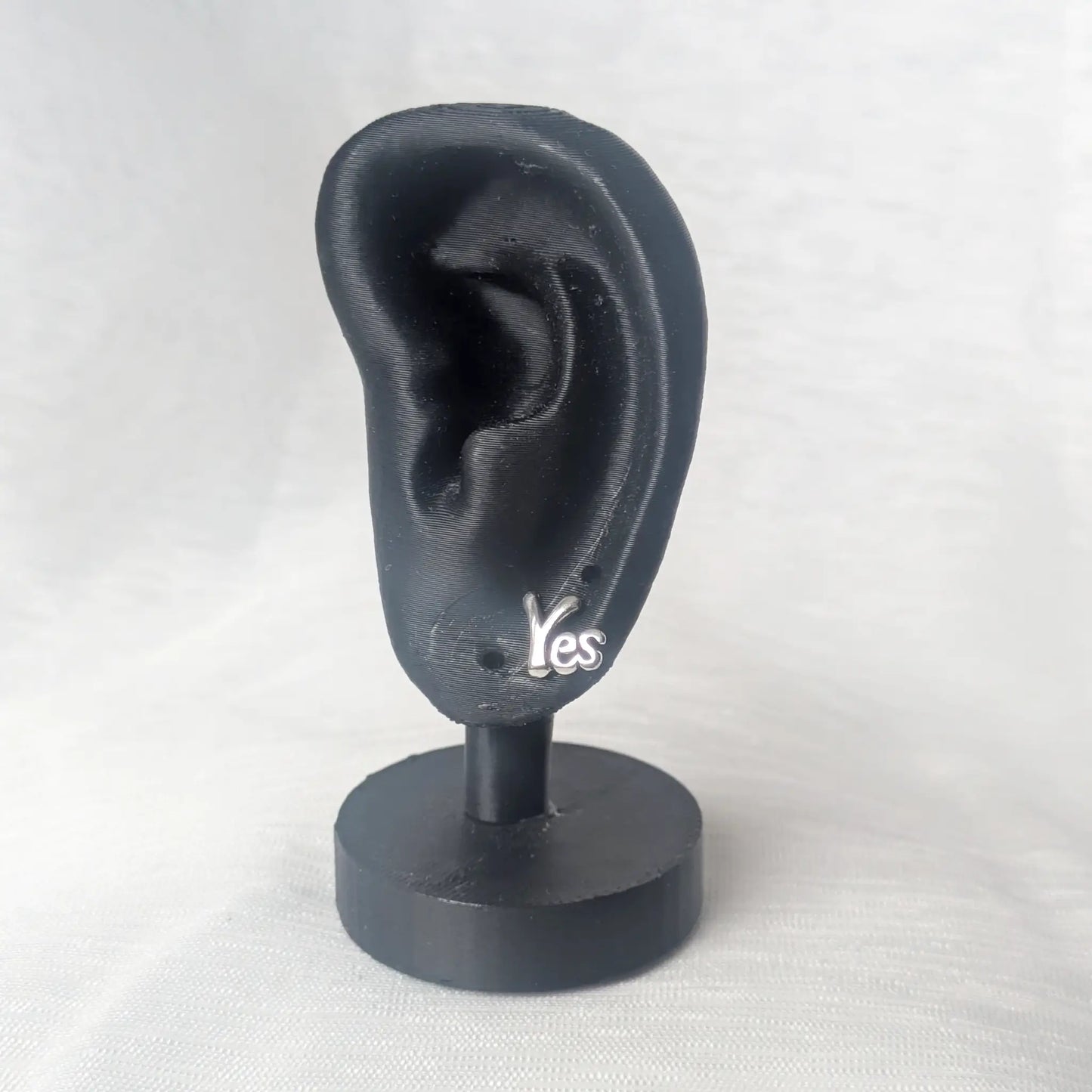 Der silberne No-Ohrstecker präsentiert an einem schwarzen Ohr-Display.