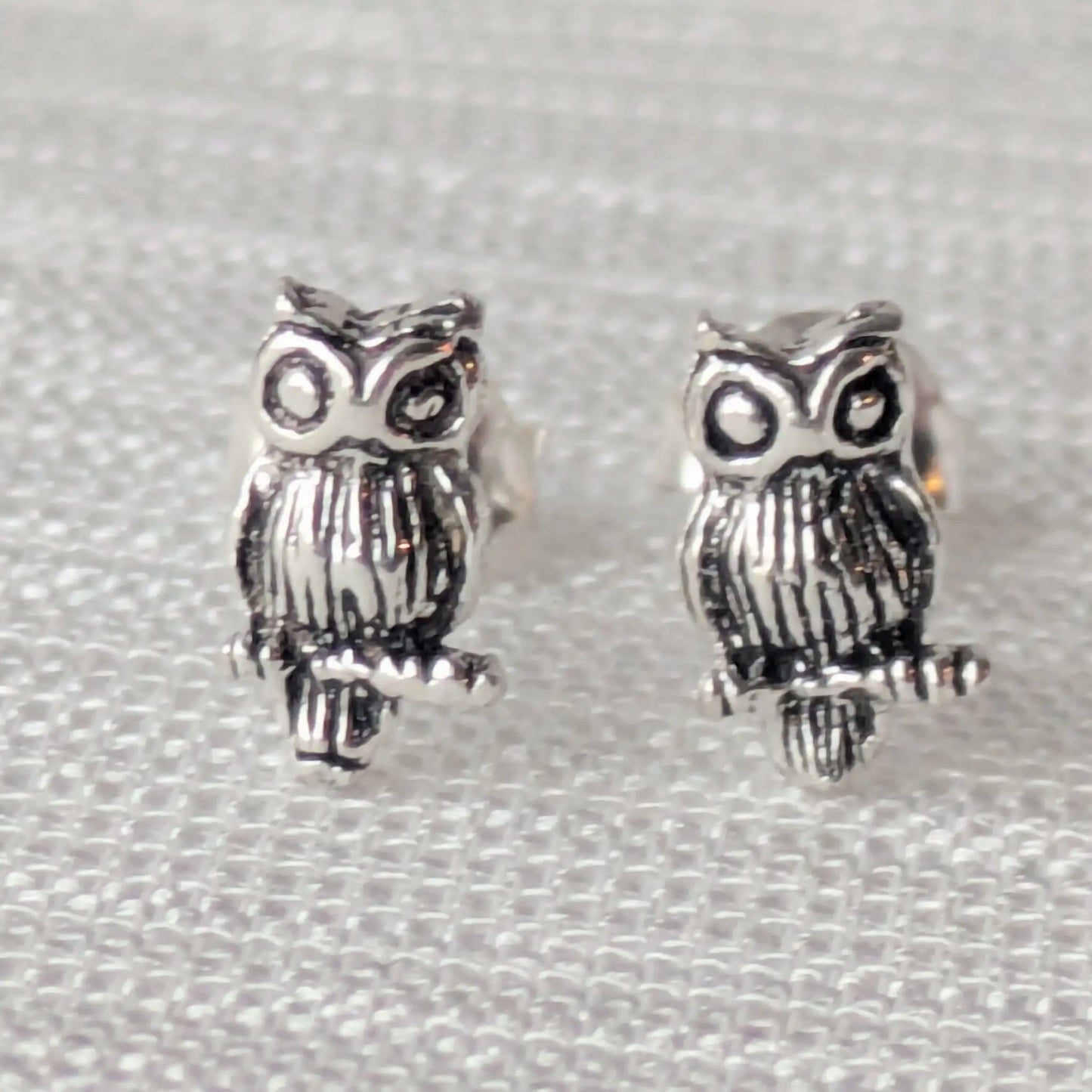 Paar detaillierte Eulen-Ohrstecker aus 925 Sterling Silber auf weißem Hintergrund.