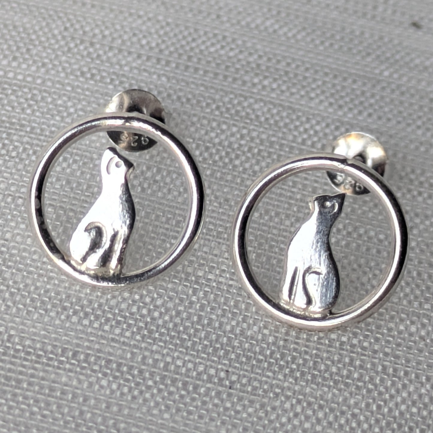 Filigrane 925-Silber Ohrstecker mit sitzender Katze im offenen Kreisdesign auf heller Stoffoberfläche