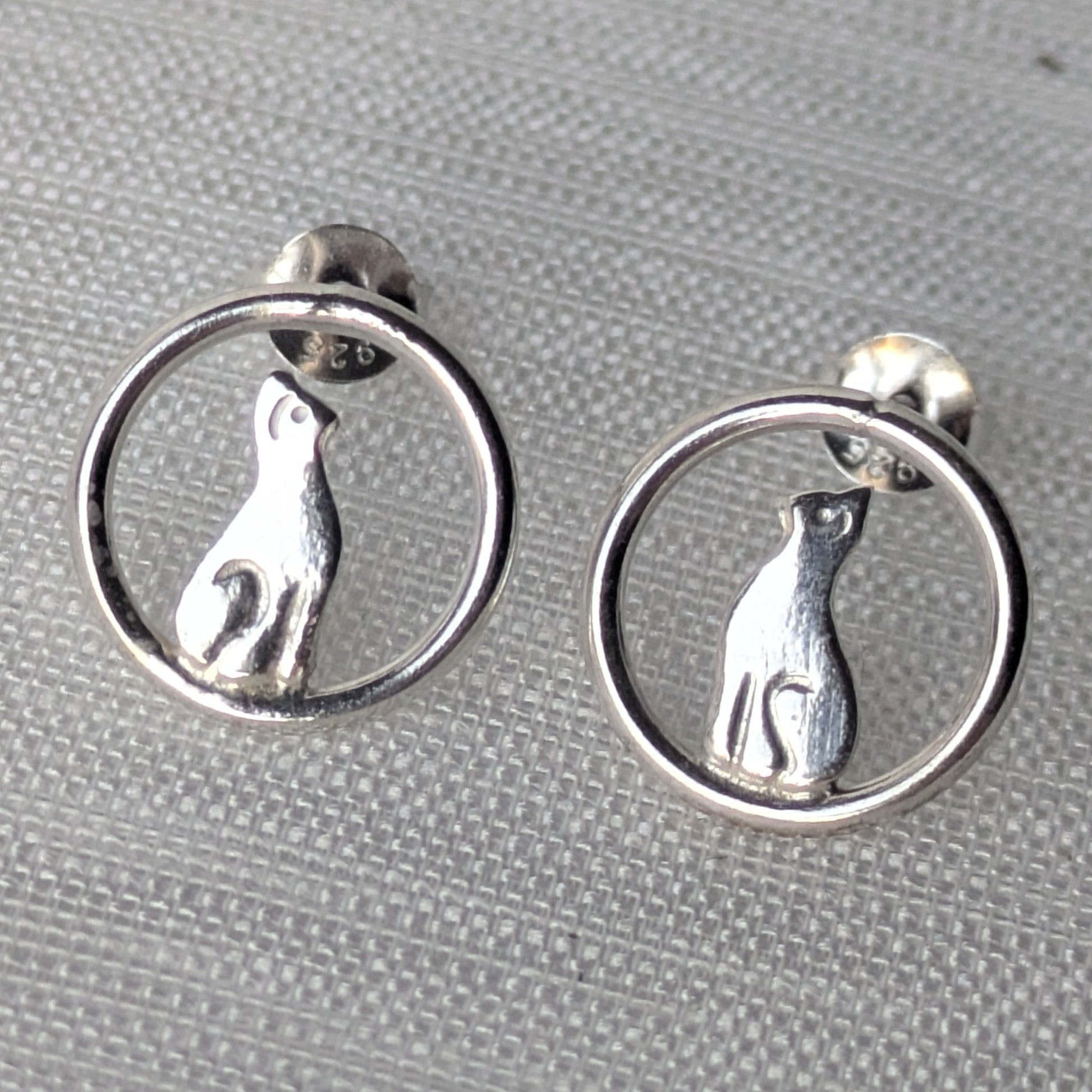 Filigrane 925-Silber Ohrstecker mit sitzender Katze im offenen Kreisdesign auf heller Stoffoberfläche