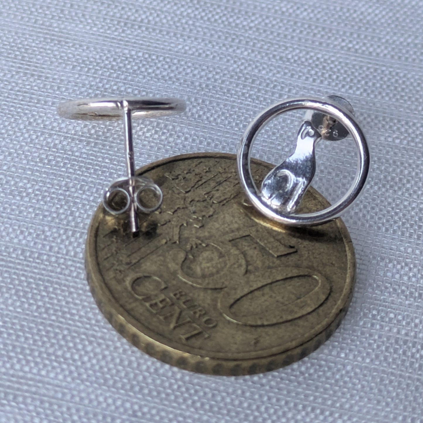 Zwei runde Silber-Ohrstecker mit eingearbeitetem Katzenmotiv, elegant präsentiert.