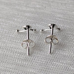 Lade das Bild in den Galerie-Viewer, Paar silberner Schleifen-Ohrstecker mit polierter Oberfläche, fotografiert auf Textil
