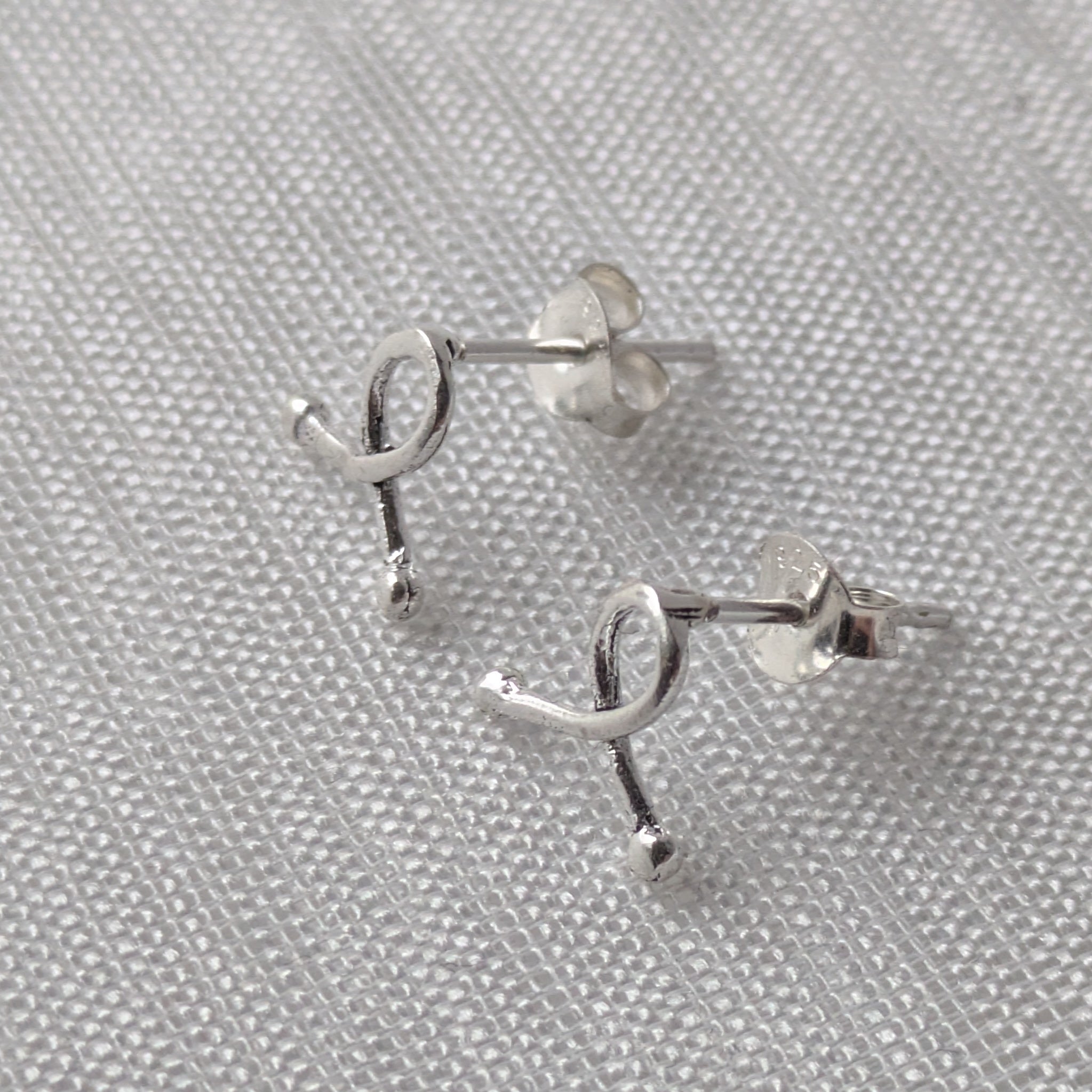 Silberne Schleifen-Ohrringe mit glänzender Oberfläche, stilvoll arrangiert