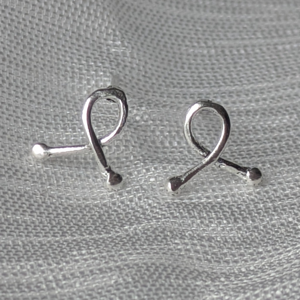 Mini-Ribbon Ohrstecker aus 925er Silber auf hellem Stoffhintergrund