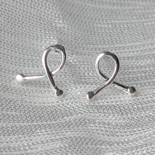 Mini-Ribbon Ohrstecker aus 925er Silber auf hellem Stoffhintergrund