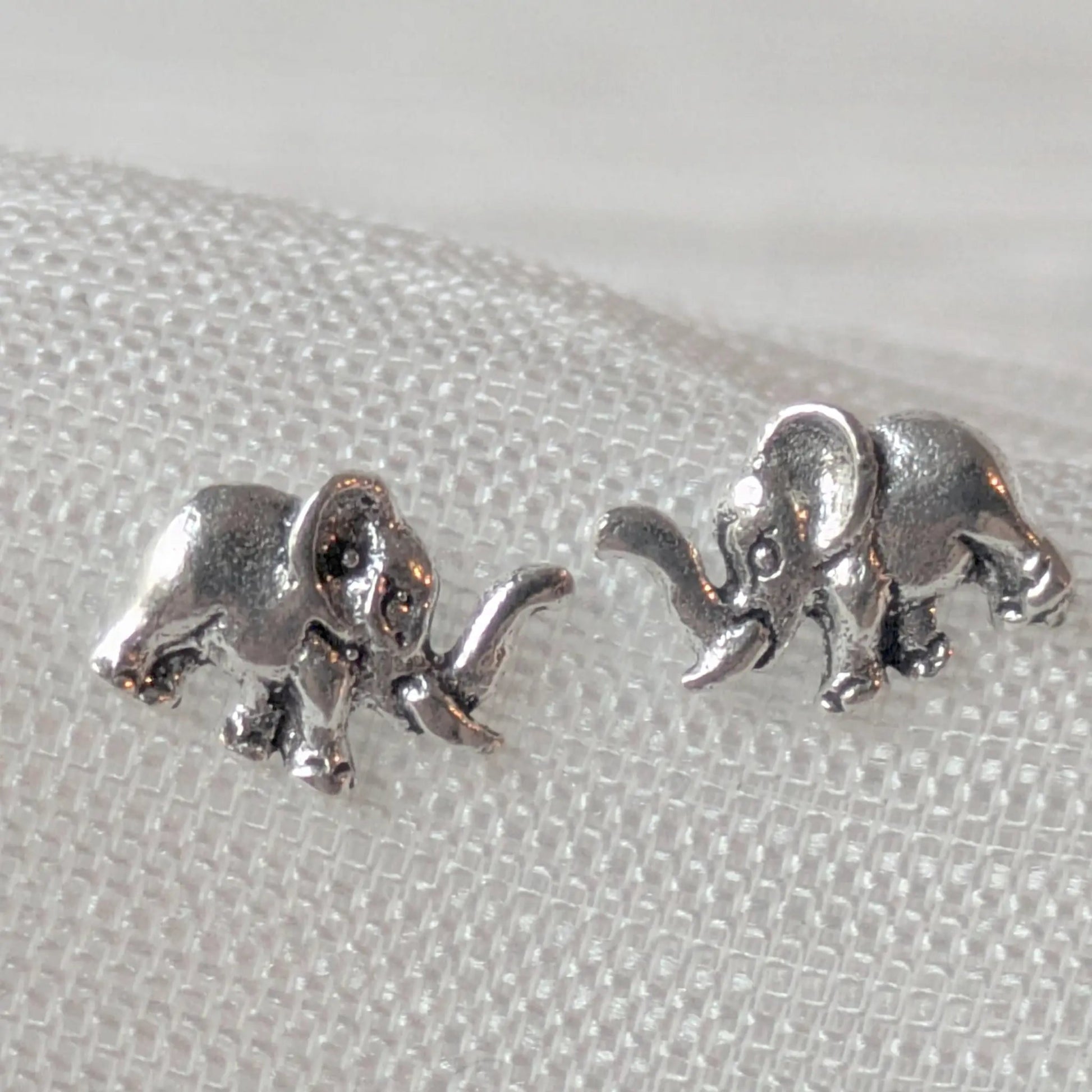 Nahaufnahme von zwei kleinen Elefanten-Ohrringen aus echtem Silber, ideal als Ohrstecker für Tierliebhaber.