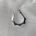 Lade das Bild in den Galerie-Viewer, Design-Creolen aus poliertem Silber mit kantiger Struktur, fotografiert auf Textil
