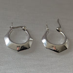 Lade das Bild in den Galerie-Viewer, Reflektierende Silberohrringe mit eckigem Design, liegend auf hellem Stoff
