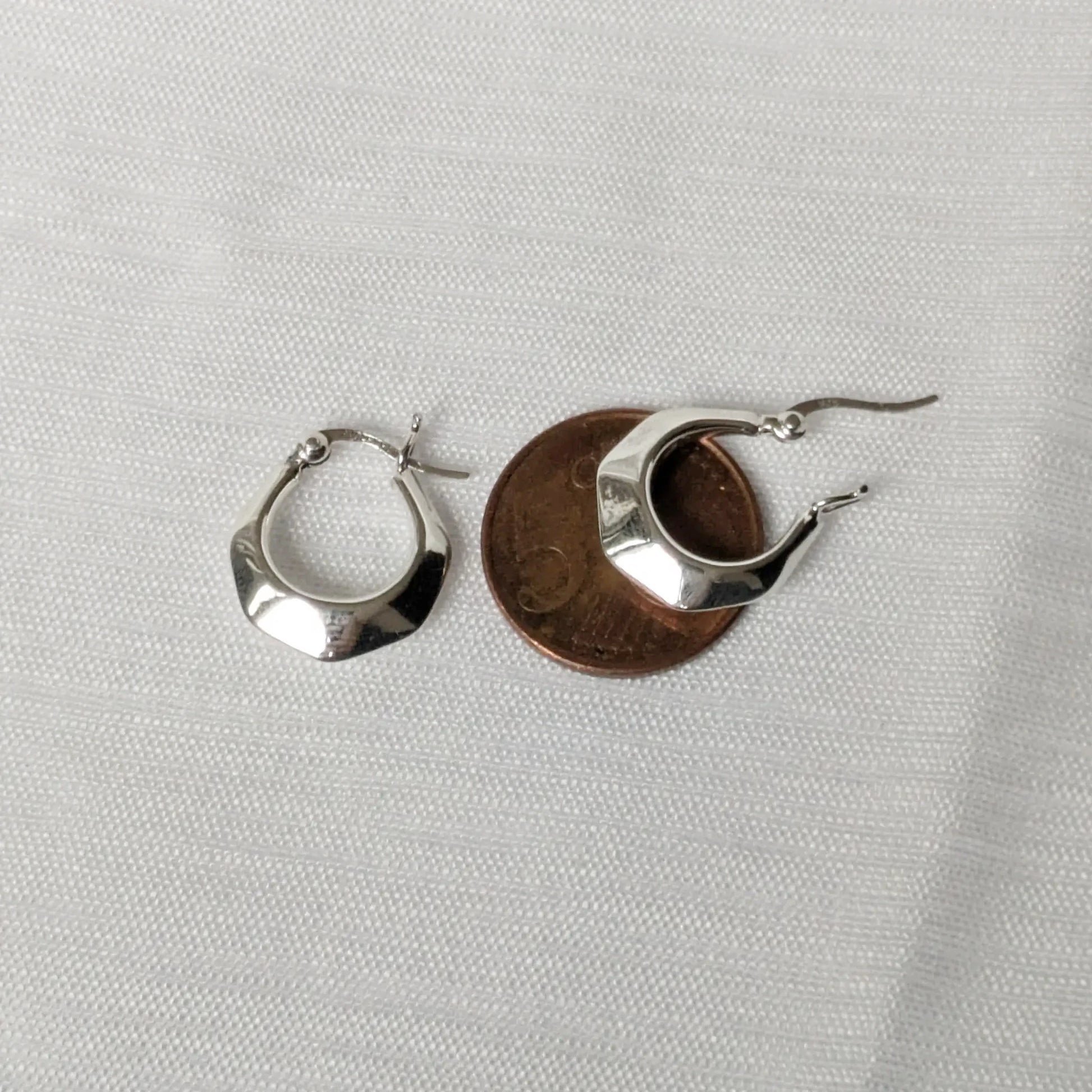 Größenvergleich der kleinen Silber-Ohrringe auf einer 5-Cent-Münze zur Veranschaulichung.