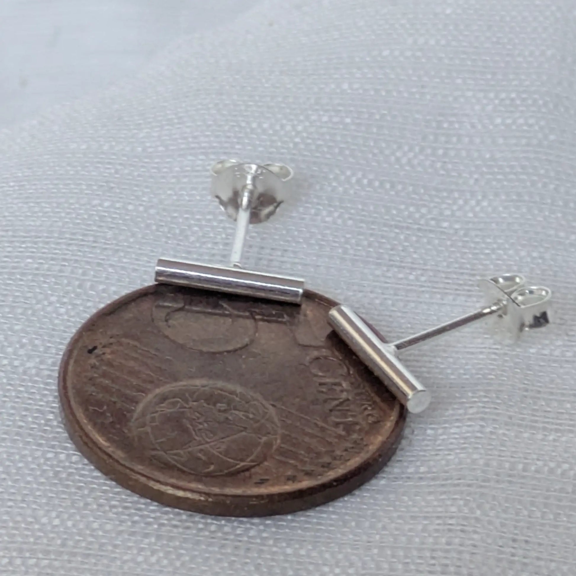Größenvergleich der minimalistischen Silber-Ohrringe 10mm auf einer 5-Cent-Münze zur Maßstäblichkeit.