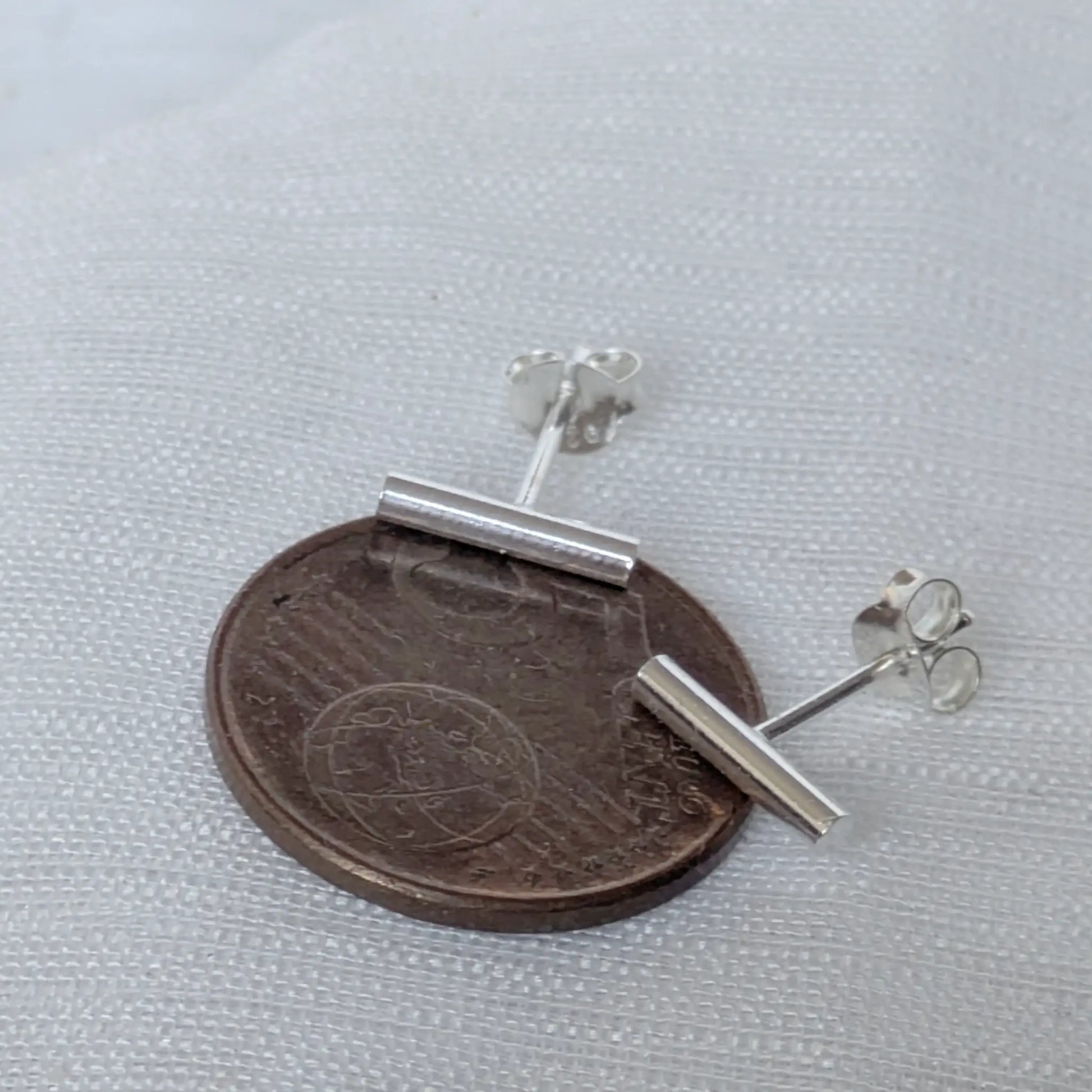Größenvergleich der minimalistischen Silber-Ohrringe 12mm auf einer 5-Cent-Münze zur Maßstäblichkeit.