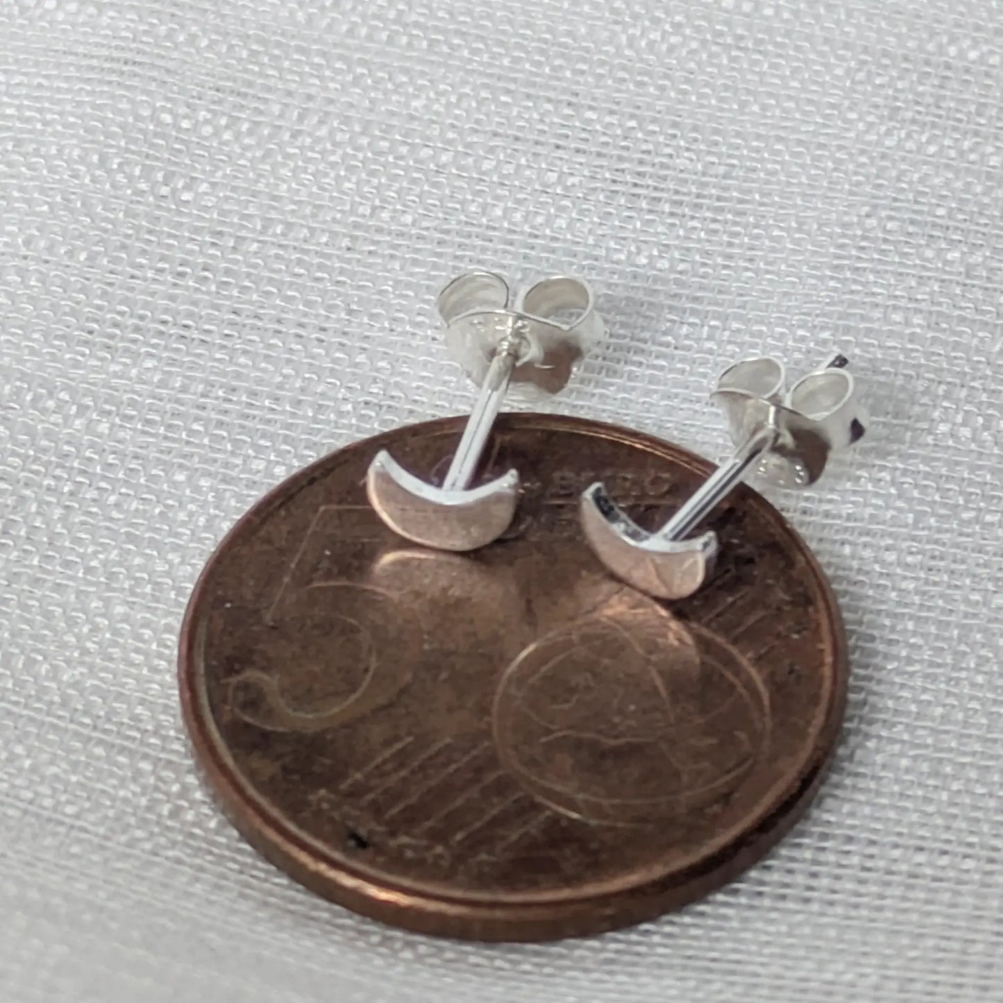 Größenvergleich der kleinen Mondsichel-Ohrstecker auf einer 5-Cent-Münze.
