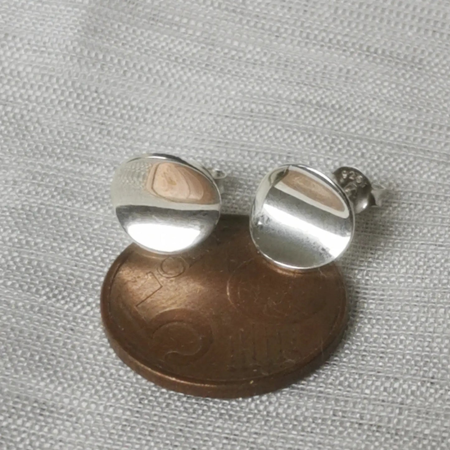 Größenvergleich der runden Silber-Ohrstecker auf einer 5-Cent-Münze für die Maßstäblichkeit.