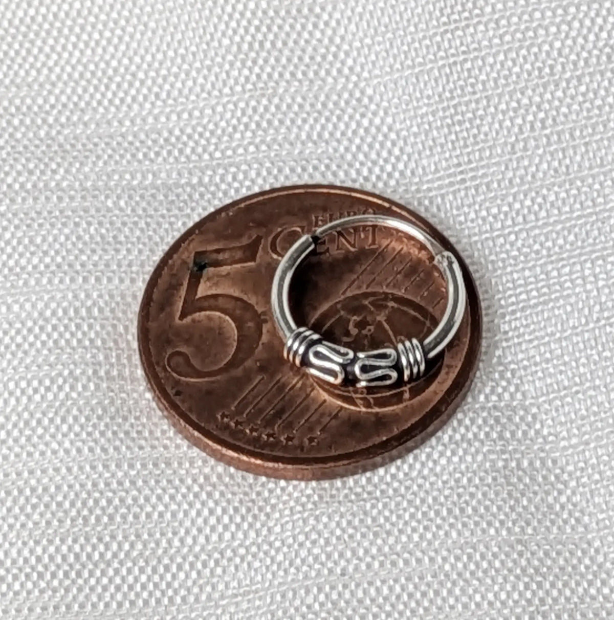 Größenvergleich: Detailreiche Bali Silbercreolen im Vintage-Look liegend auf einer 5-Cent-Münze