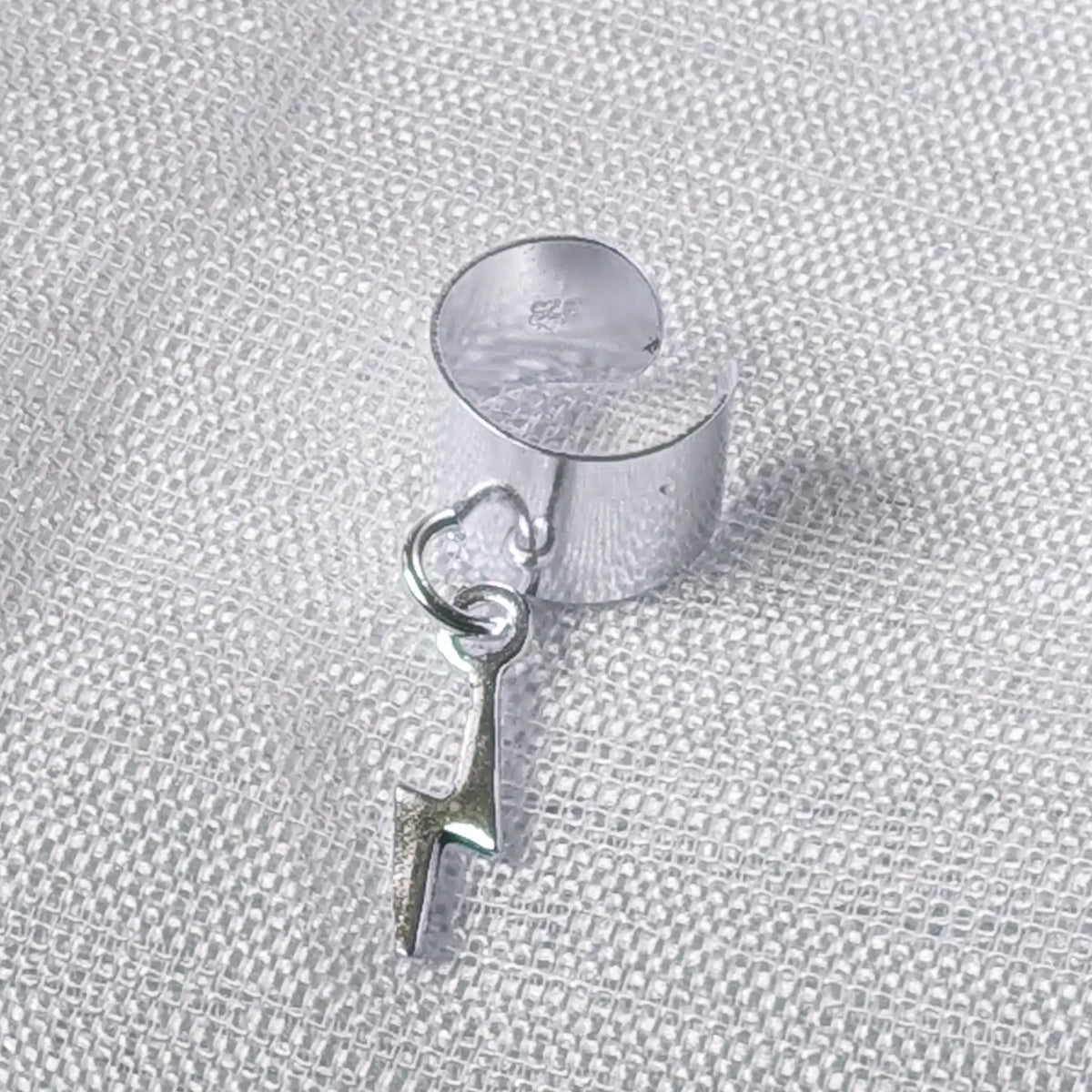 Detaillierte Nahaufnahme einer breiten 925 Silber Ohrklemme mit frei schwingendem Blitz-Anhänger und 925-Prägung auf der Innenseite.