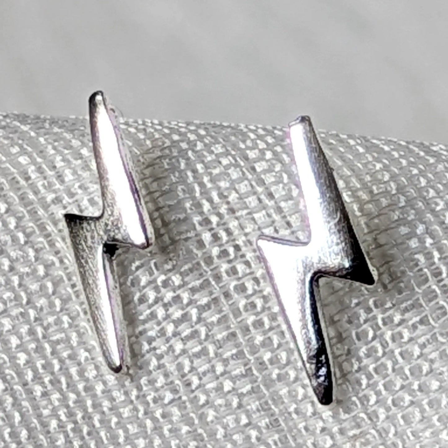 Detailierte Nahaufnahme von zwei hochglanzpolierten Blitz Ohrsteckern aus echtem 925 Sterling Silber.