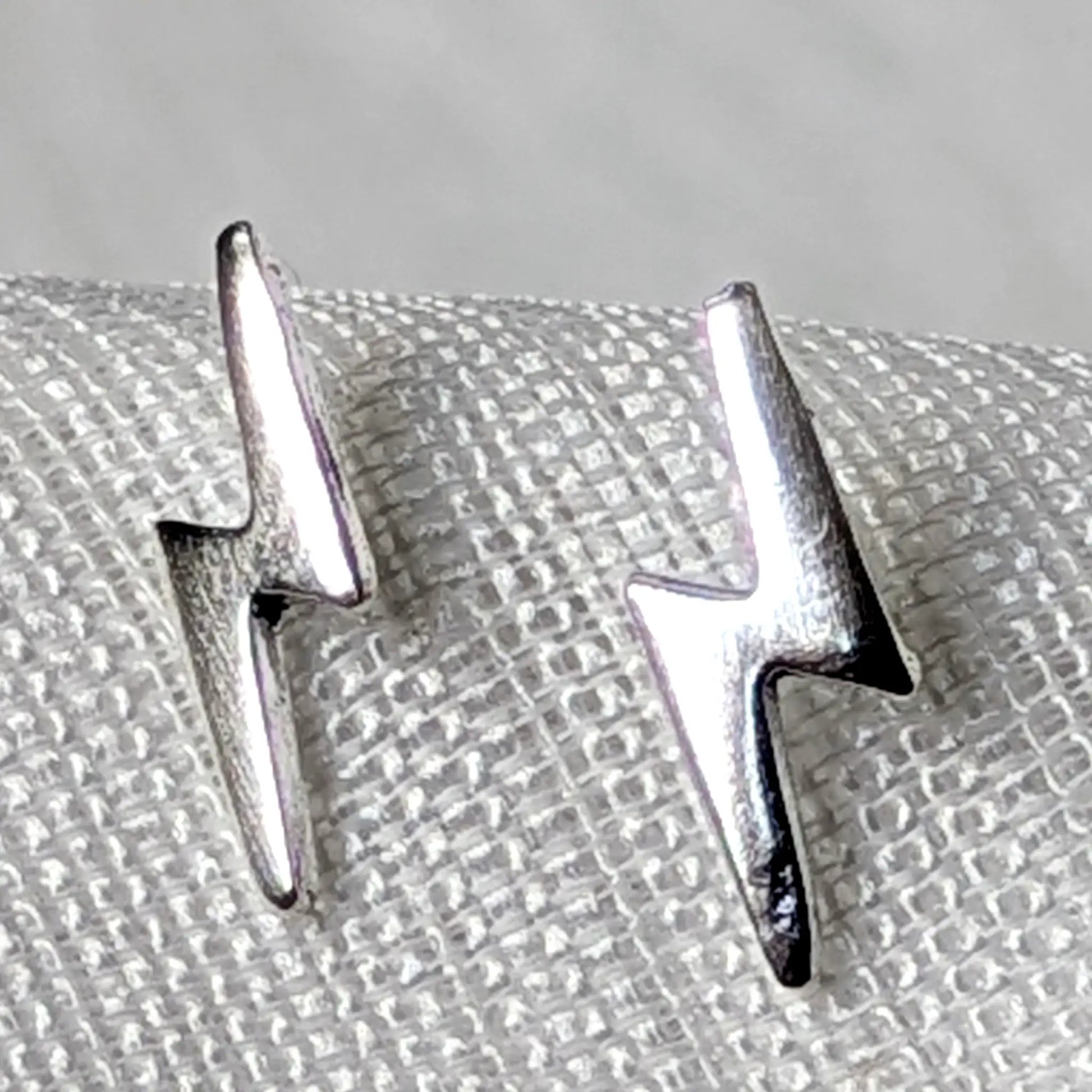 Detailierte Nahaufnahme von zwei hochglanzpolierten Blitz Ohrsteckern aus echtem 925 Sterling Silber.