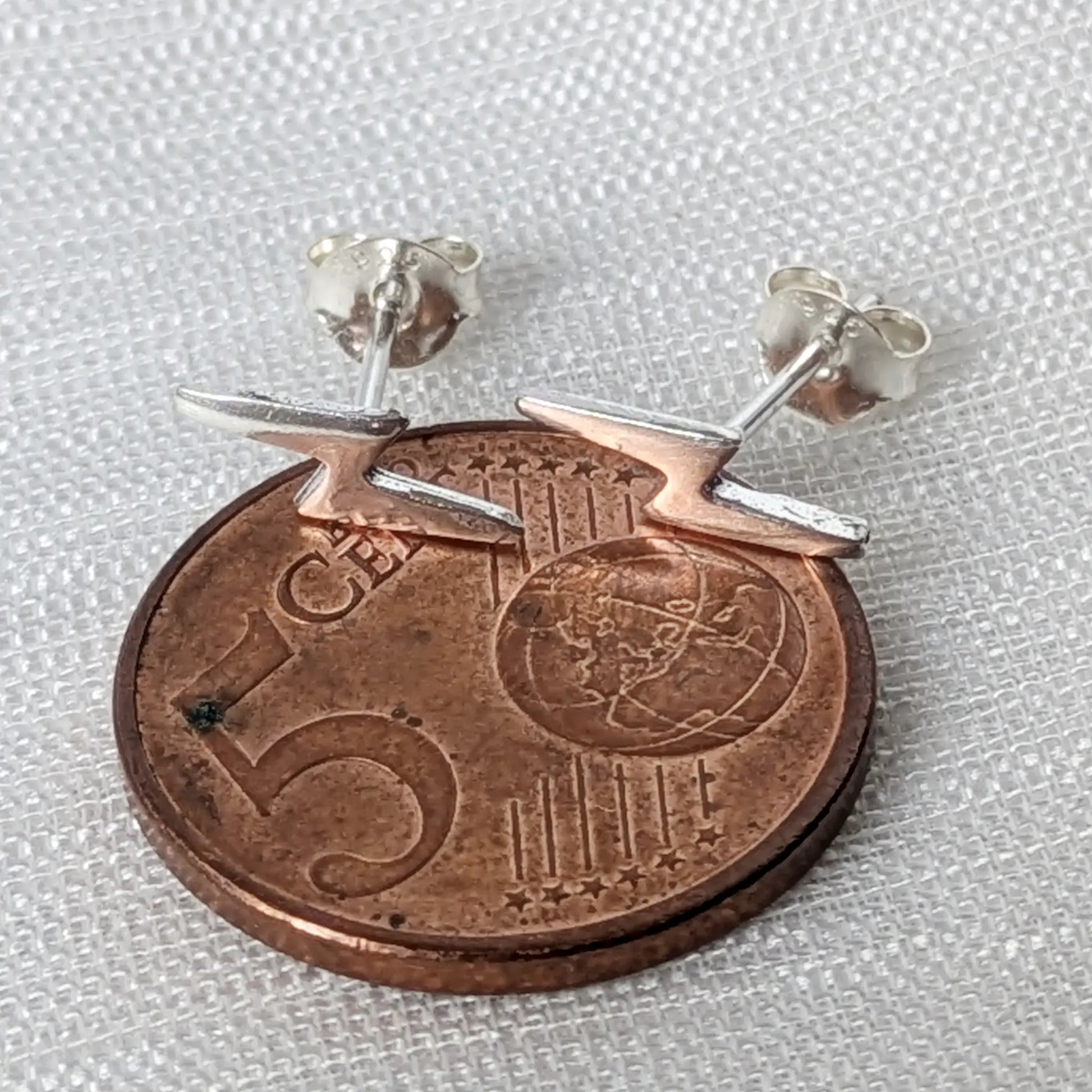 Größenvergleich der zarten, kleinen Blitz-Ohrringe aus 925er Silber platziert auf einer 5-Cent-Münze.