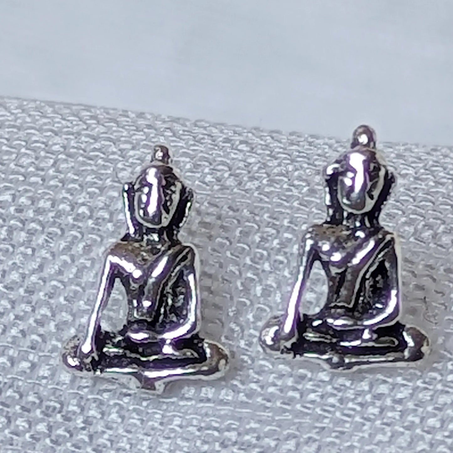 Nahaufnahme der 925 Silber Buddha Ohrstecker mit meditierender Figur im Lotussitz.