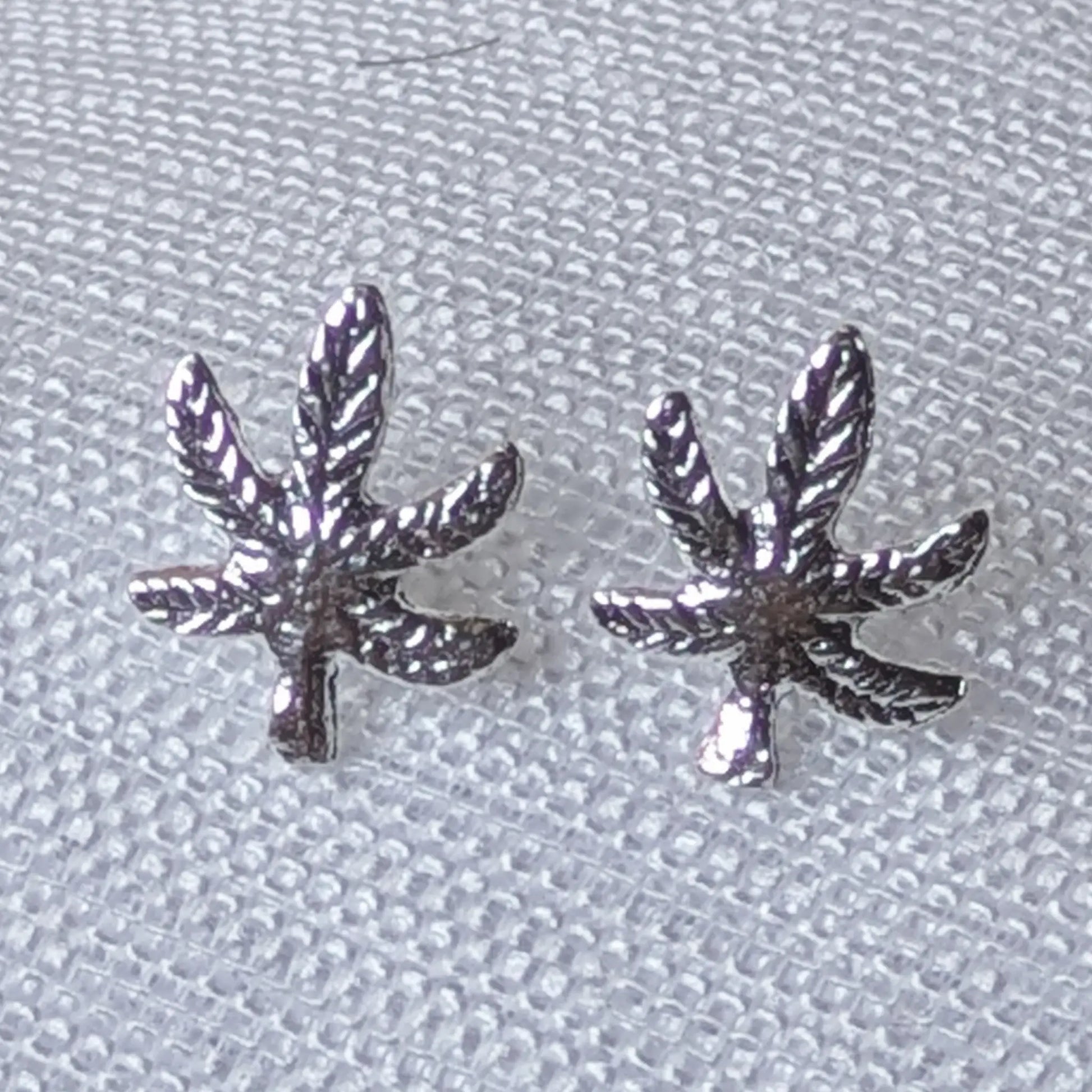 Nahaufnahme Cannabis Ohrstecker aus 925 Silber mit detaillierter Hanfblatt-Struktur