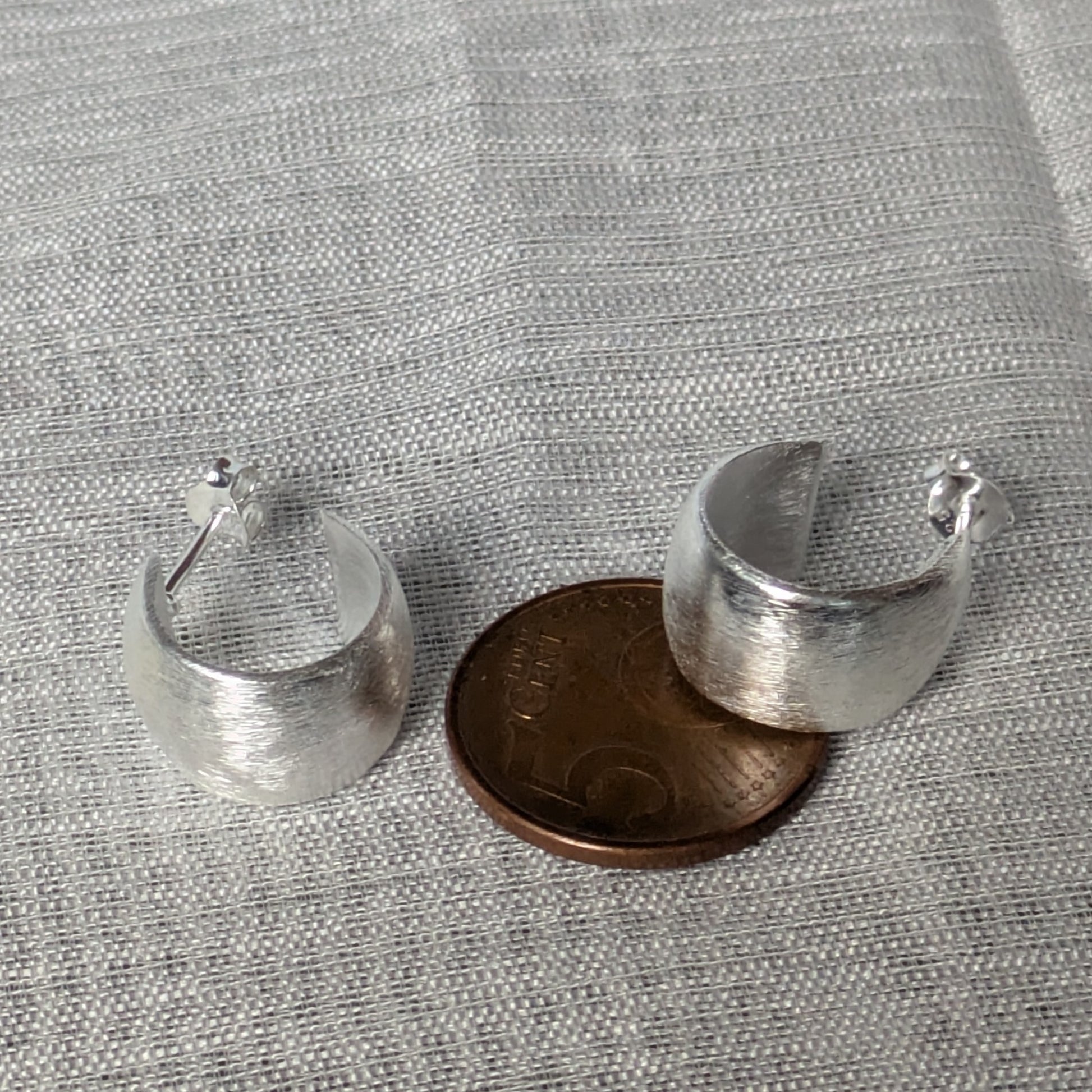 Matte 925‑Silber‑Creolen im minimalistischen Stil, liegend auf 5-Cent Münze