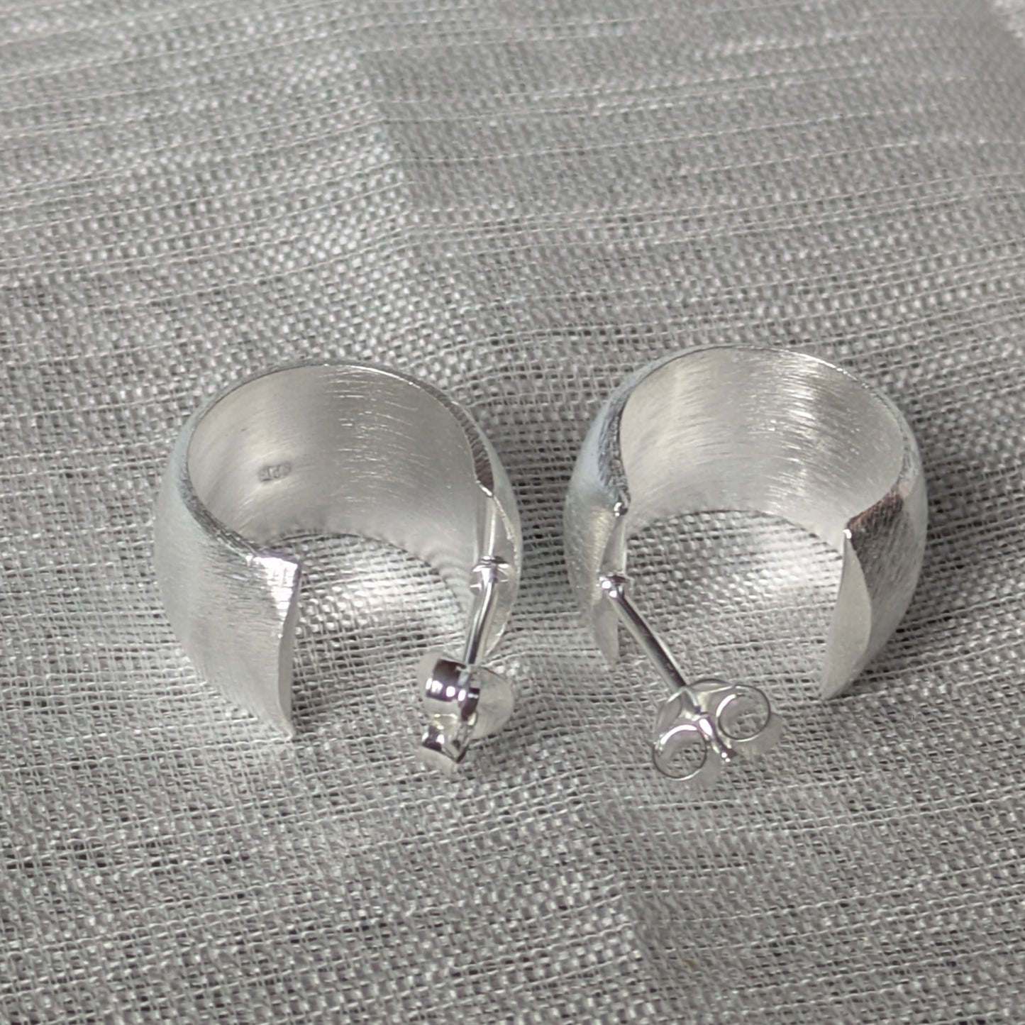 Minimalistische Creolen aus Sterling Silber mit gebürstetem Finish auf Textiluntergrund