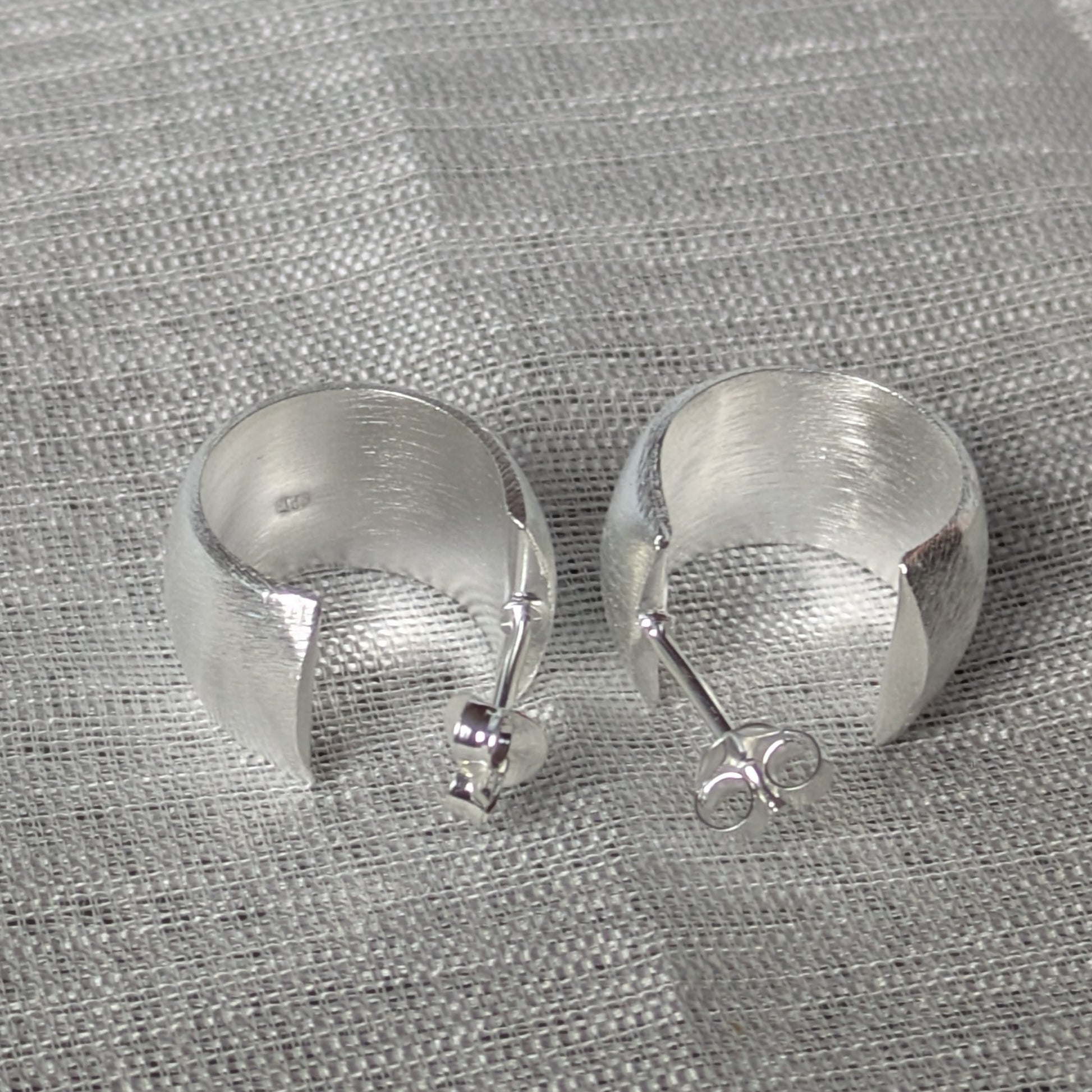 Minimalistische Creolen aus Sterling Silber mit gebürstetem Finish auf Textiluntergrund