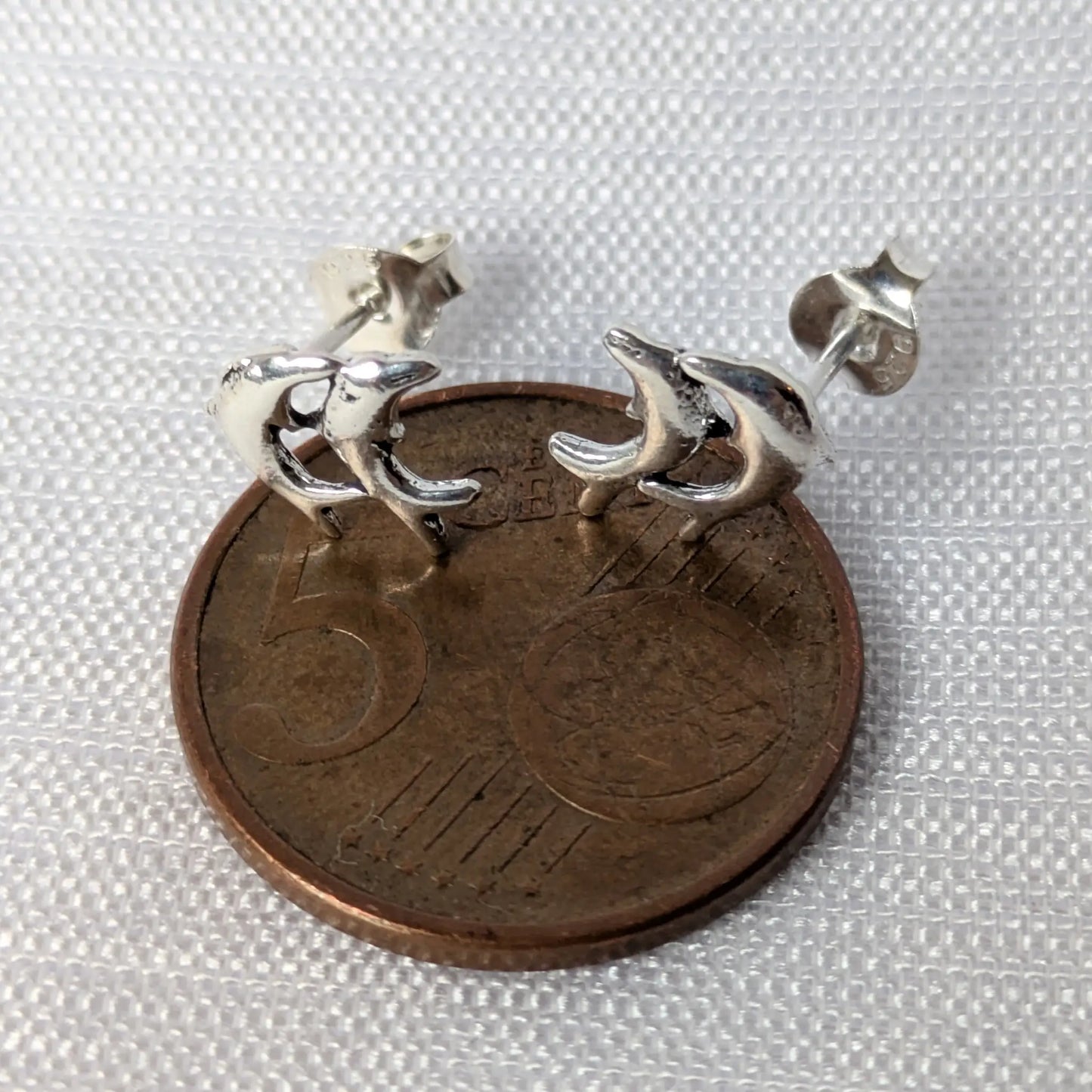 Größenvergleich Delfine Ohrstecker auf einer 5-Cent-Münze.