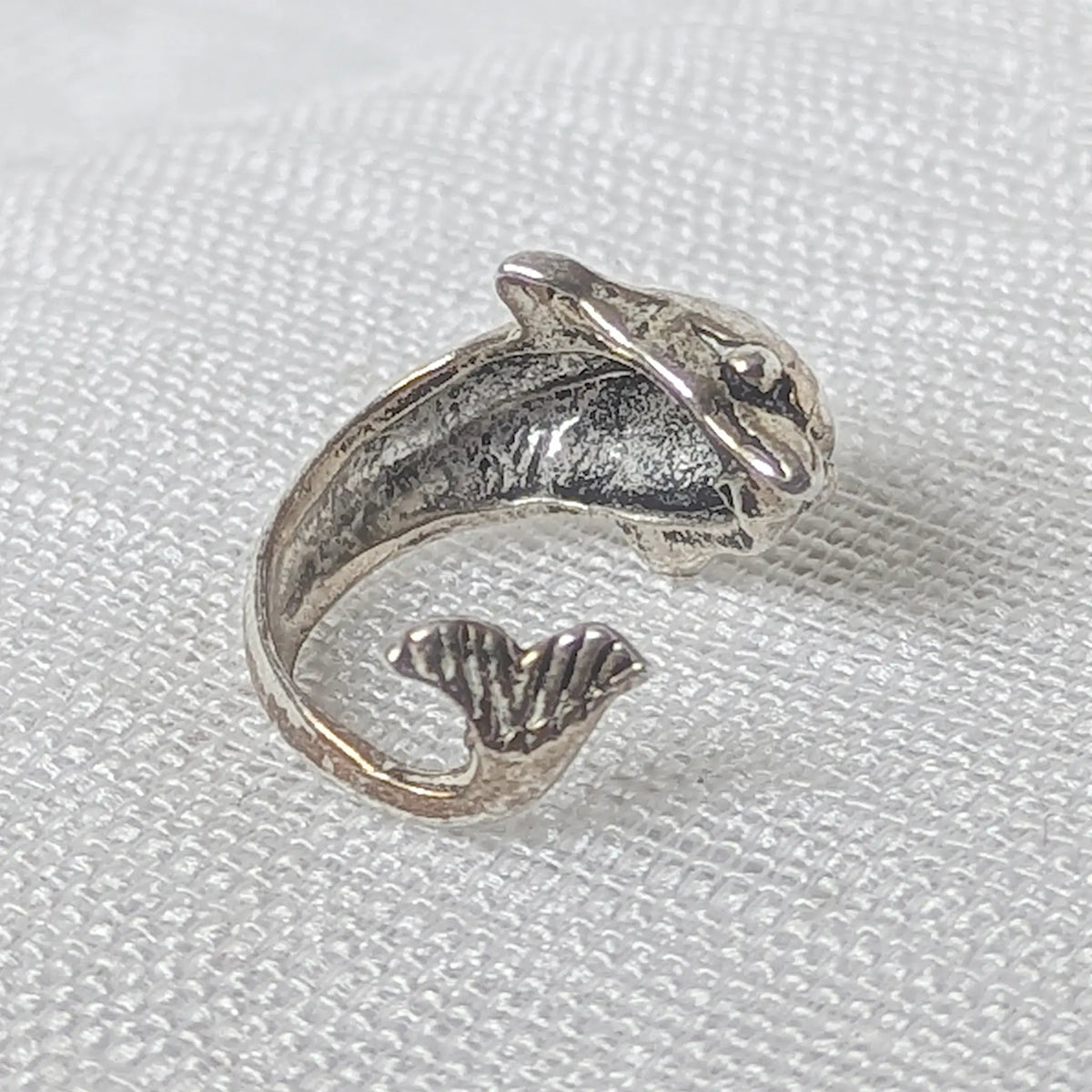 Nahaufnahme der geschwungenen Silber Ohrklemme im 3D Delfin-Design aus 925 Sterling Silber.