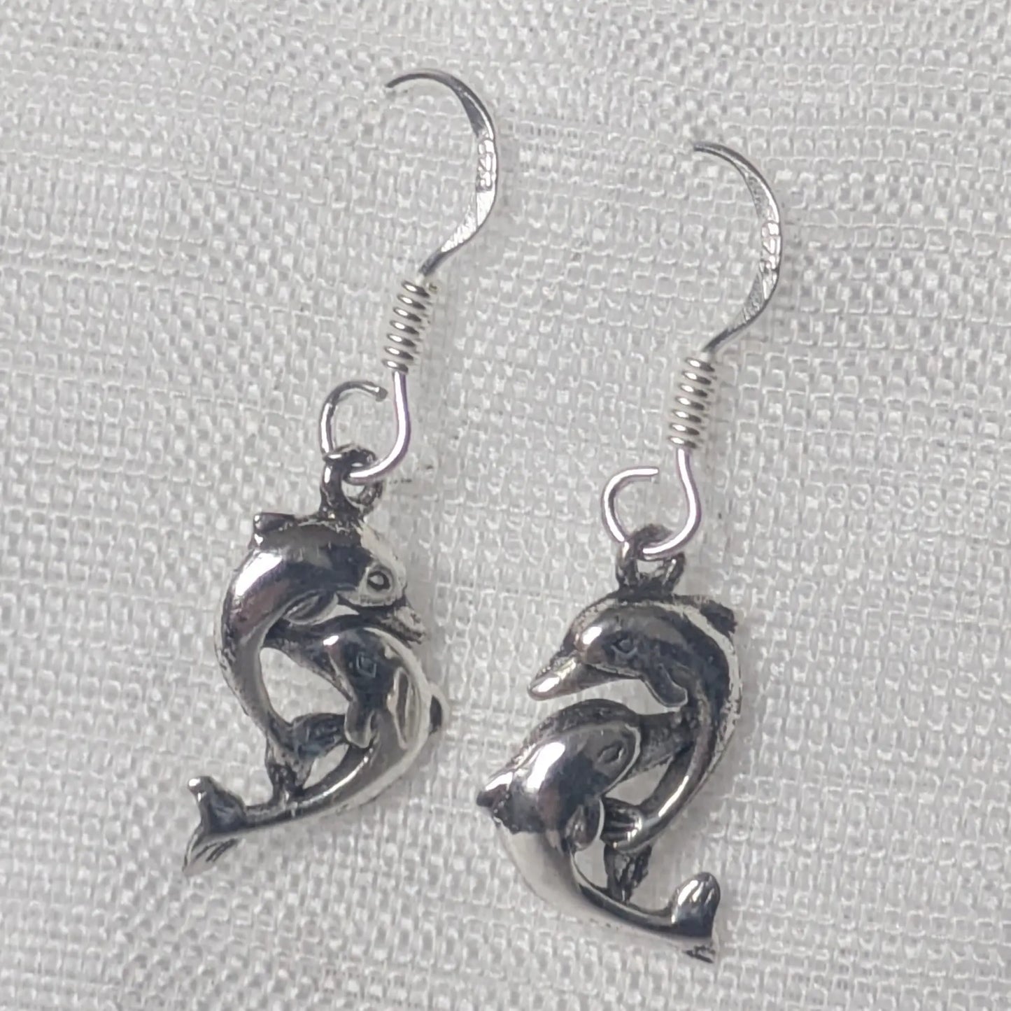 Detaillierte Nahaufnahme der Delfin Ohrringe aus glänzendem 925 Sterling Silber.