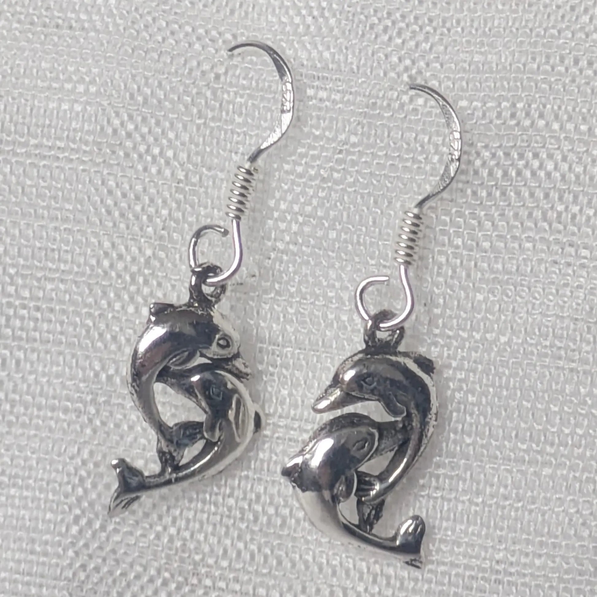 Detaillierte Nahaufnahme der Delfin Ohrringe aus glänzendem 925 Sterling Silber.