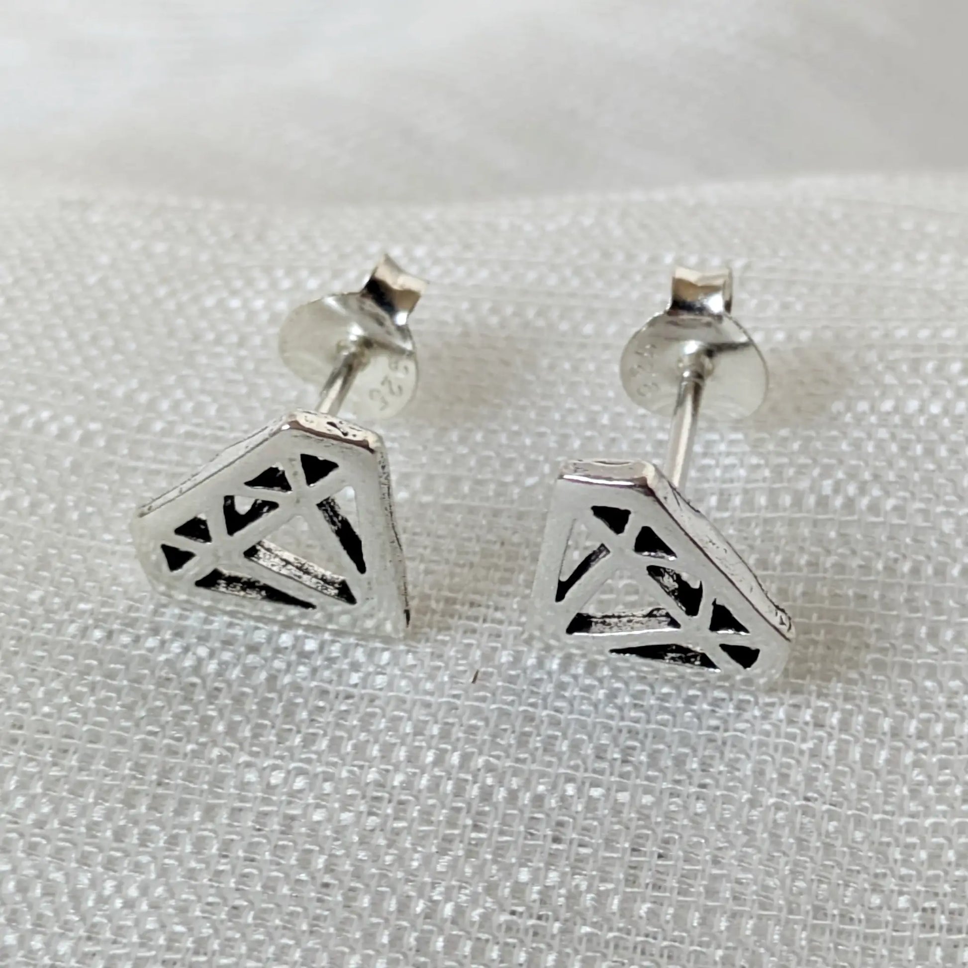 Frontalansicht der silbernen Diamond-Shape Ohrringe im filigranen, geometrischen Cutout-Design.