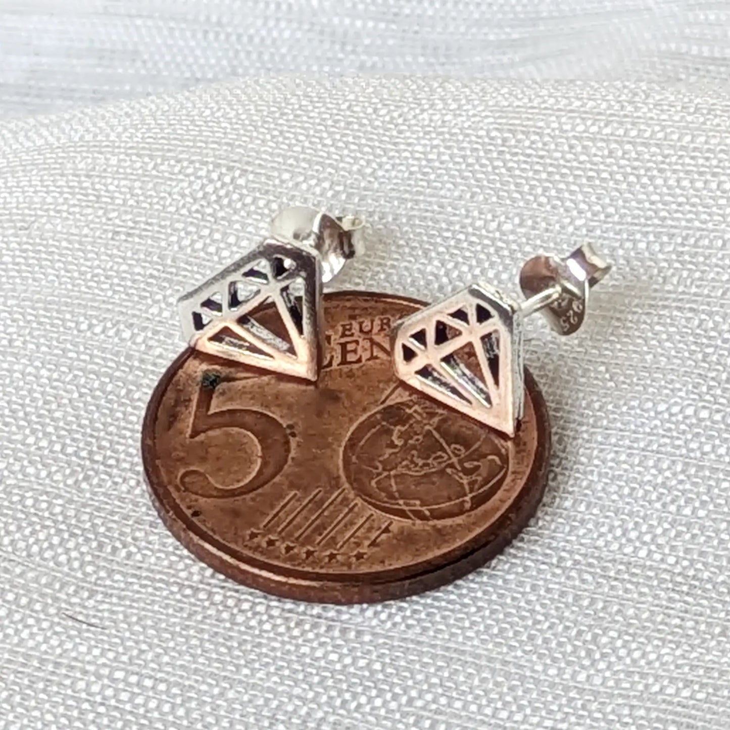 Größenvergleich der zarten, silbernen Cutout-Ohrstecker in Diamantform platziert auf einer 5-Cent-Münze.