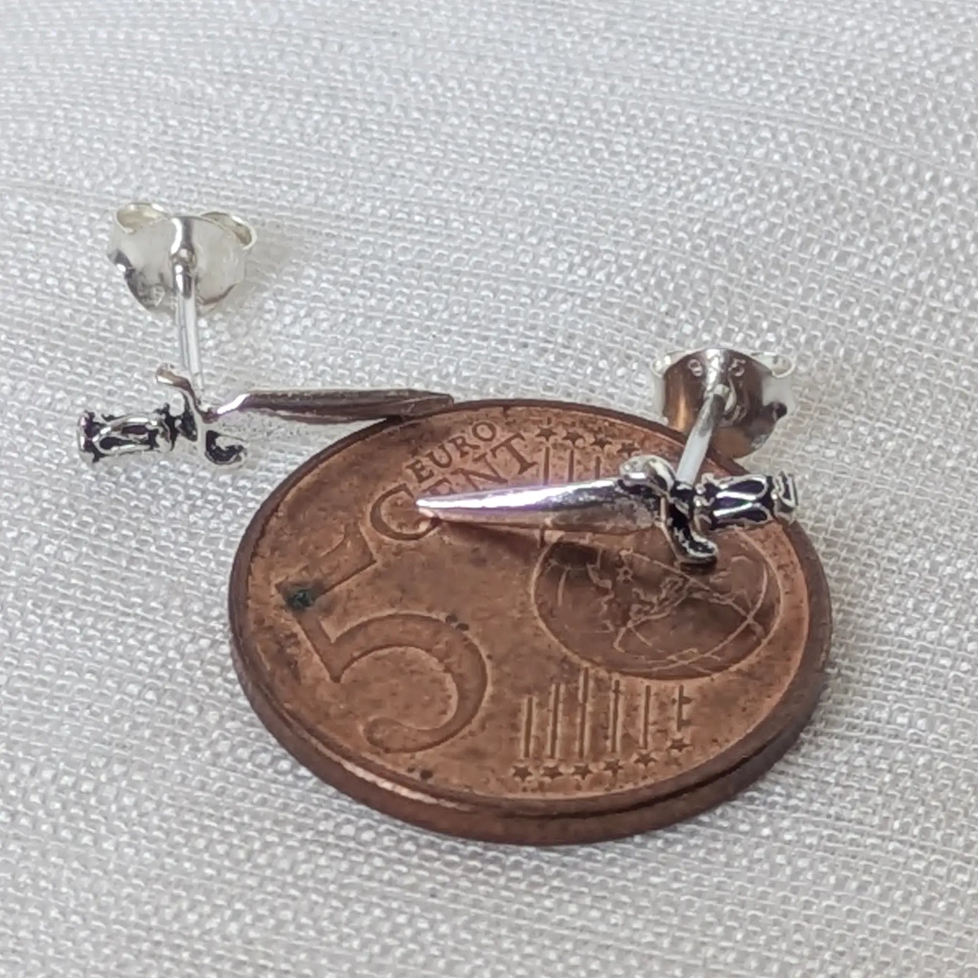 Direkter Größenvergleich der filigranen Mini-Dolch-Ohrringe aus 925 Silber liegend auf einer 5-Cent-Münze.