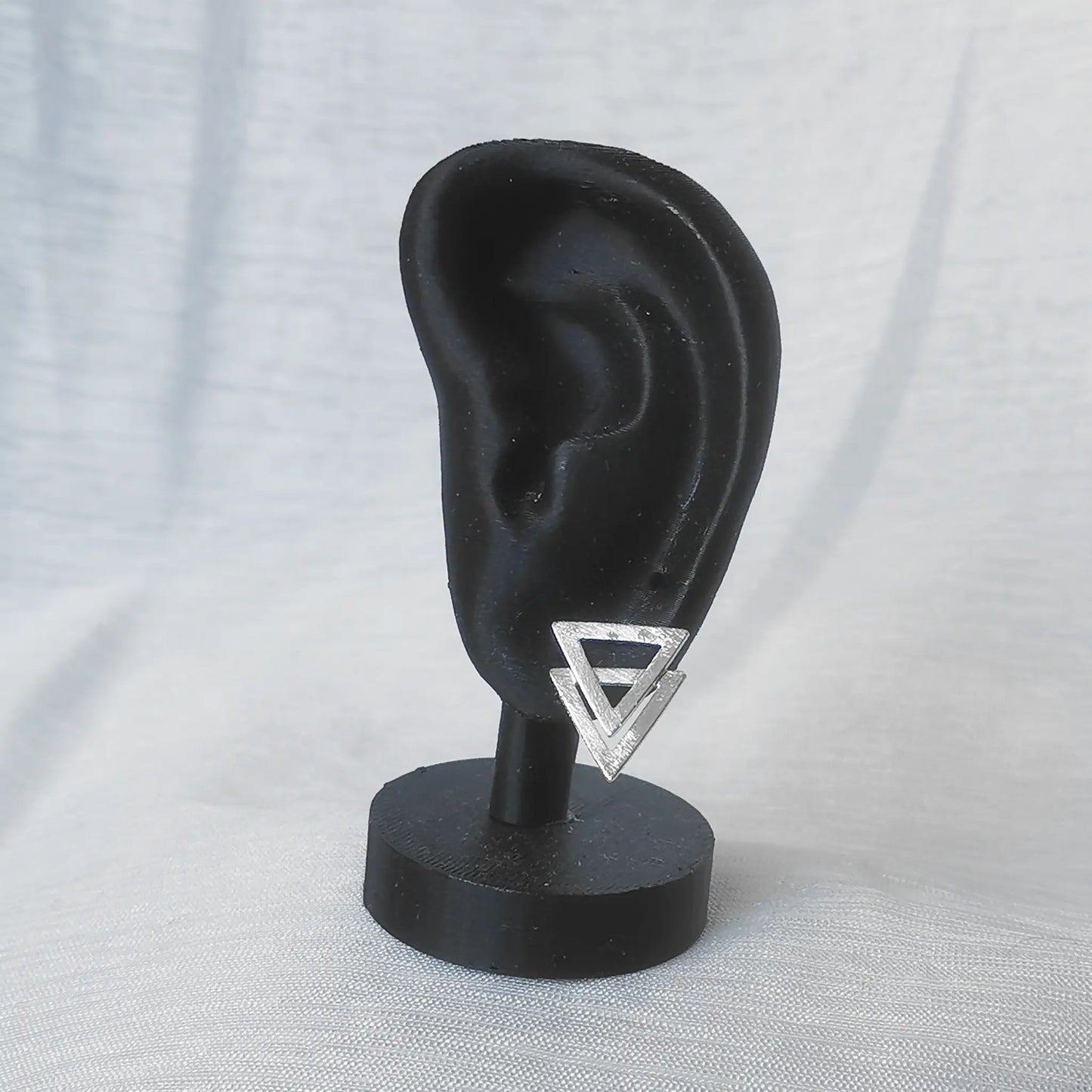 Ein mattierter 925 Silber Ohrstecker in doppelter Dreiecksform präsentiert an einem schwarzen Ohr-Display zur Veranschaulichung von Proportion und Größe.