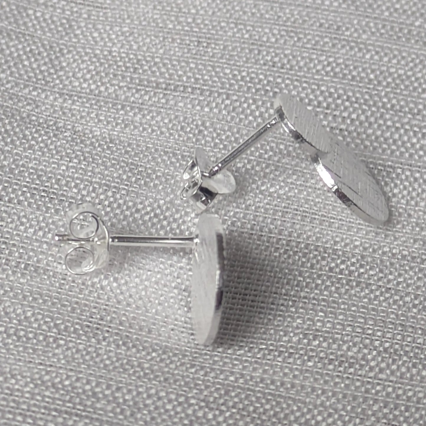 Seitenansicht der flachen silbernen Statement-Ohrstecker mit Struktur.