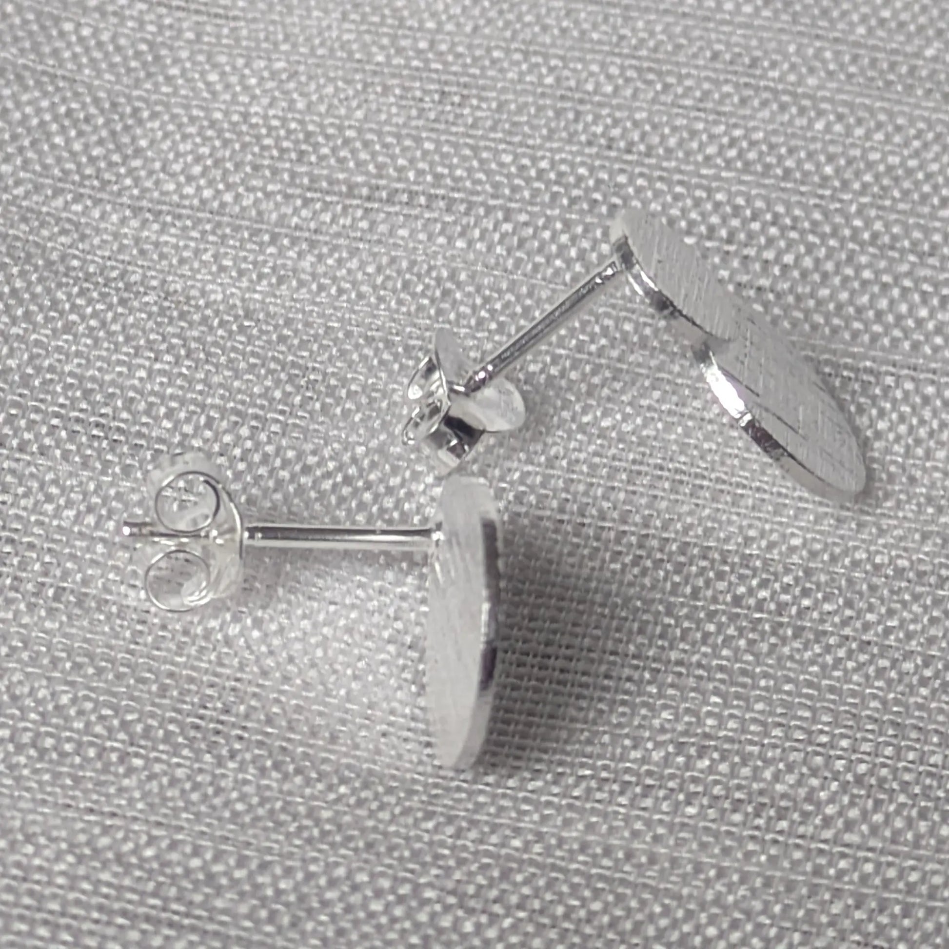 Seitenansicht der flachen silbernen Statement-Ohrstecker mit Struktur.